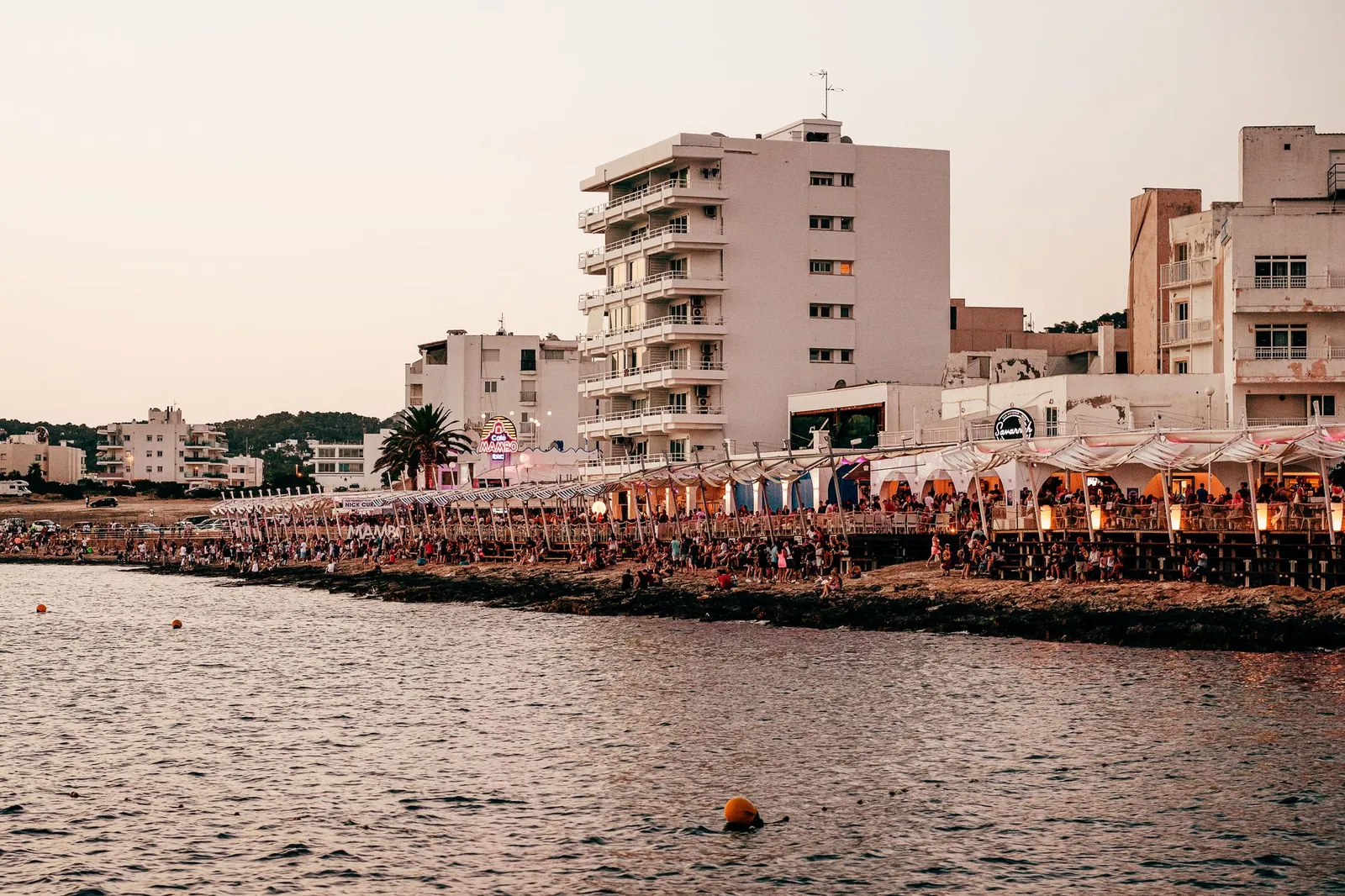 Lively Ibiza waterfront scene showcasing vibrant coastal nightlife at sunset.