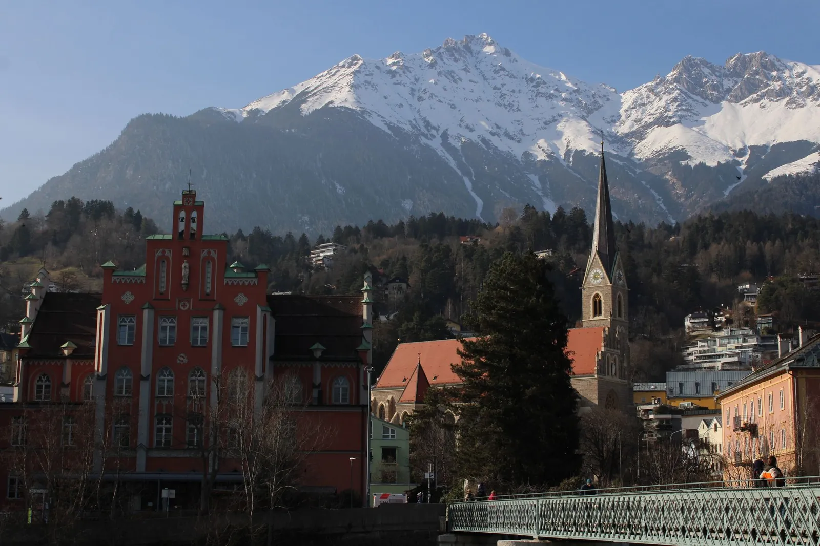 Picturesque town with mountain backdrop and church spire in winter setting.