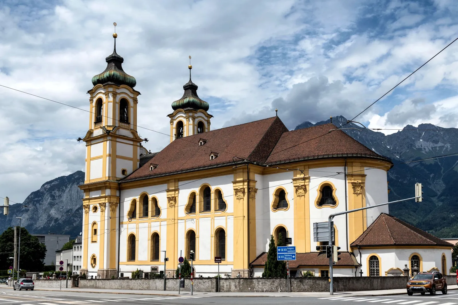 Stunning view of the baroque Wilten Basilica with mountainous backdrop in Innsbruck, Austria.