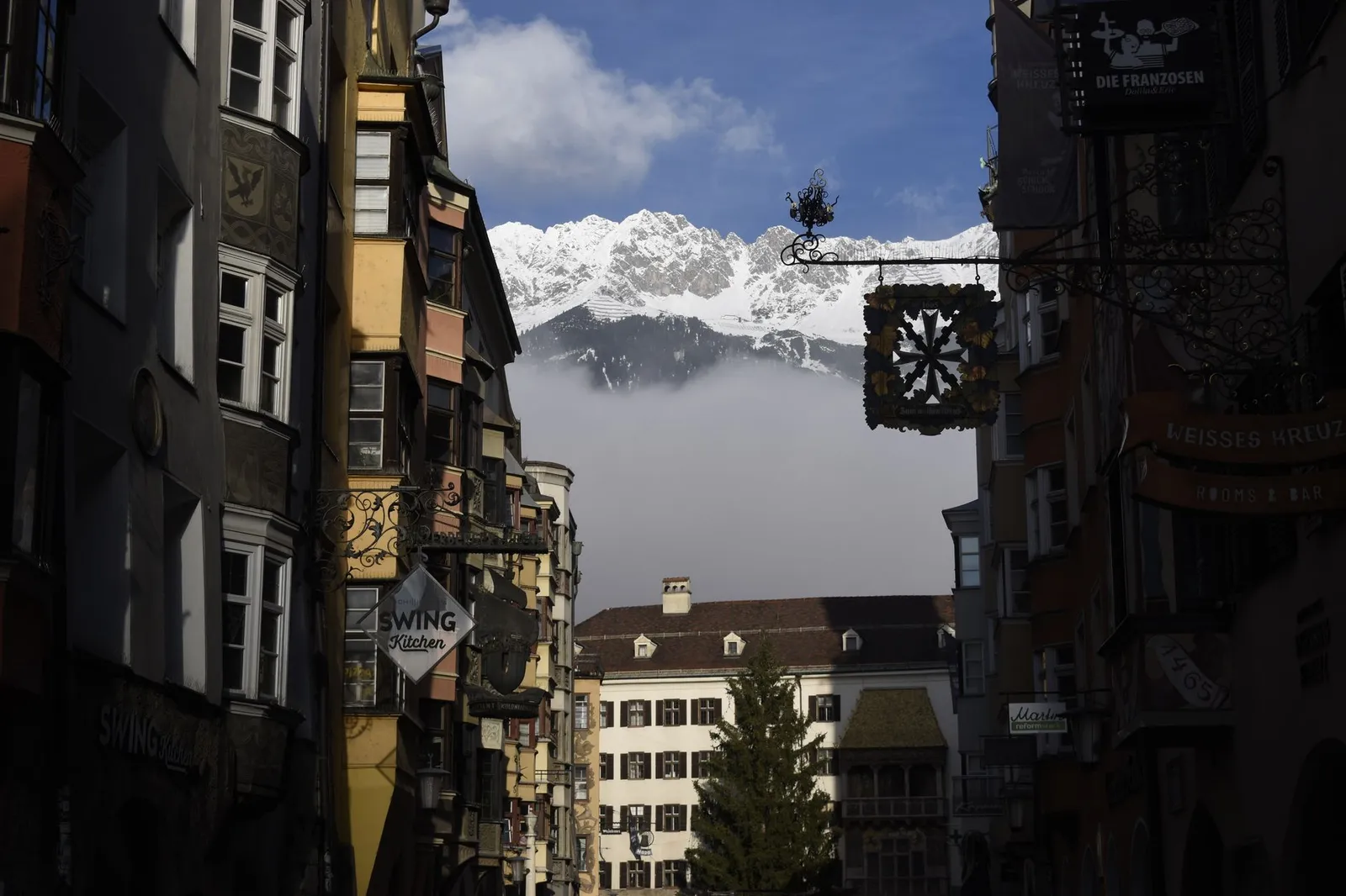 Charming view of Innsbruck's colorful streets with snow-capped mountains in the background.