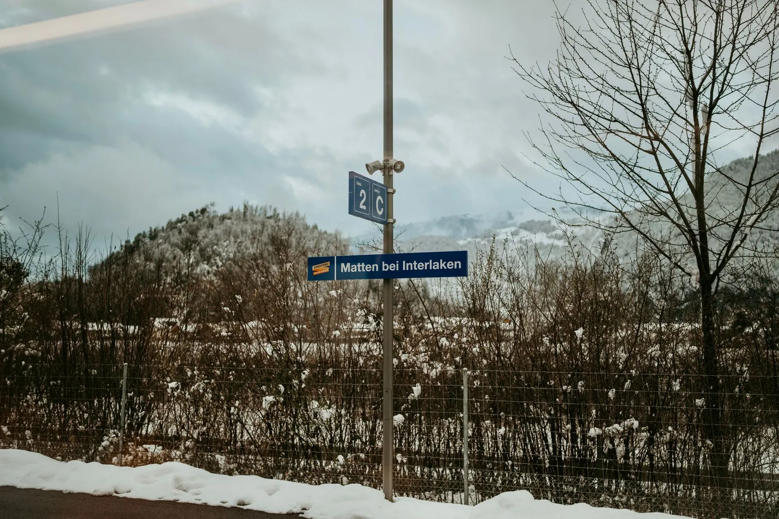 Snowy landscape in Matten bei Interlaken, Switzerland with train station sign.