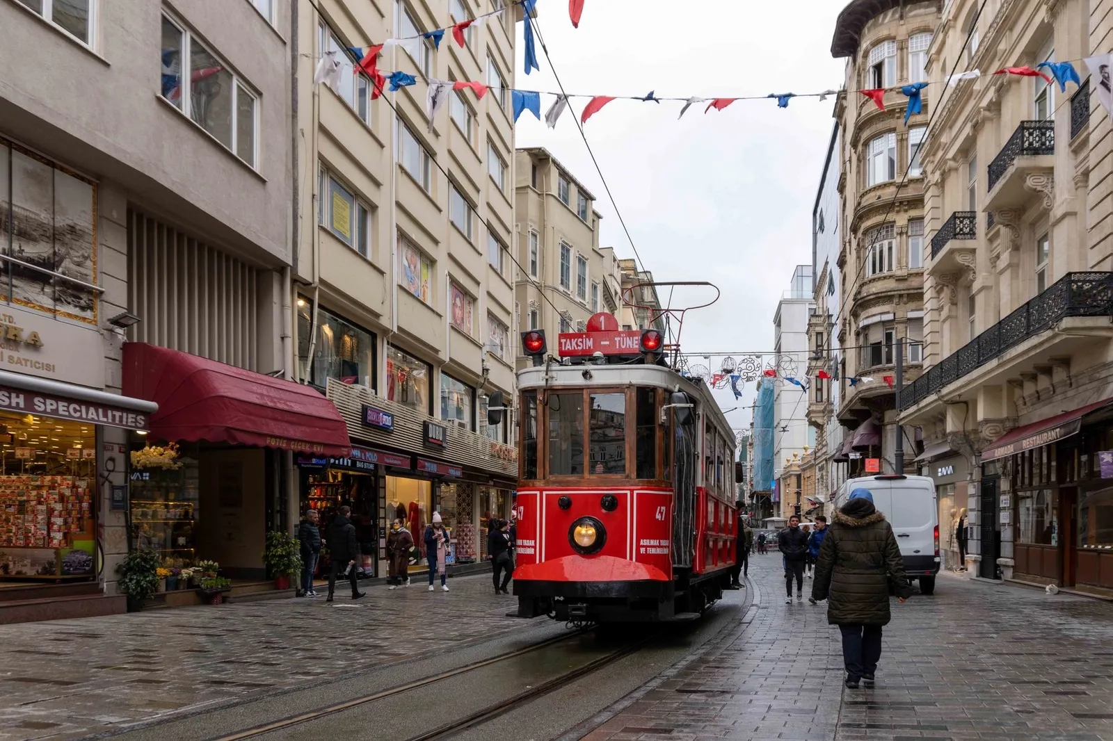 Classic red tram travels through bustling Istiklal Avenue in Istanbul.