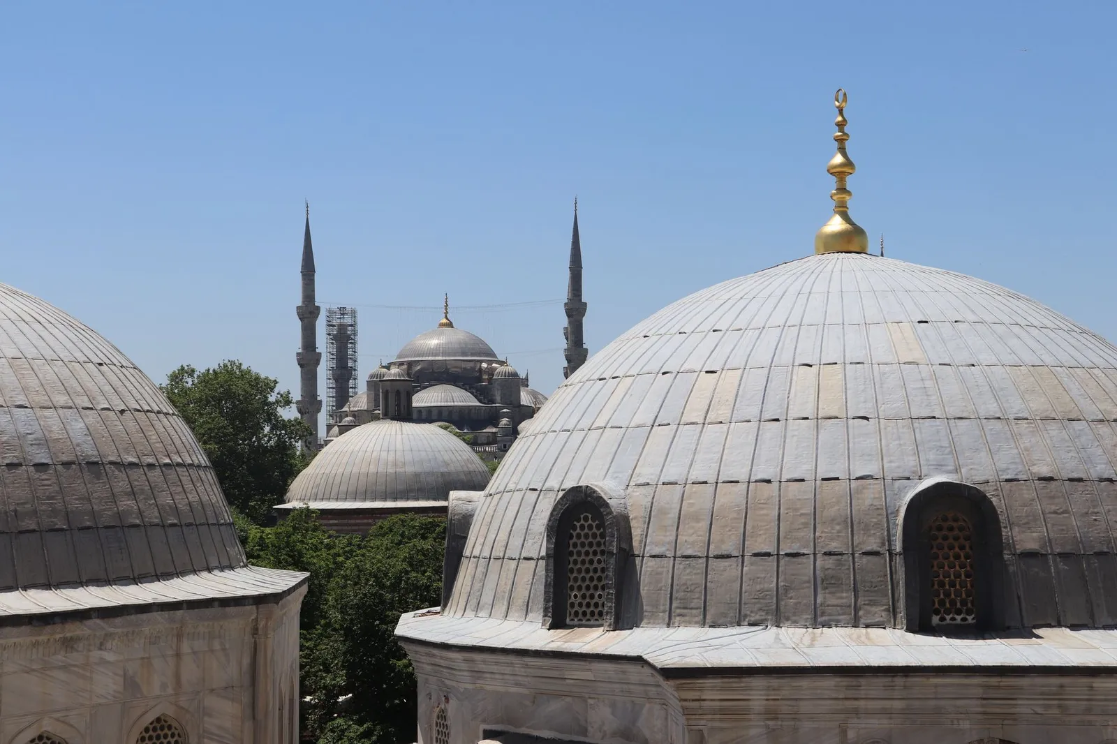 Stunning view of the iconic Sultan Ahmed Mosque domes in Istanbul, Turkey, under a clear blue sky.
