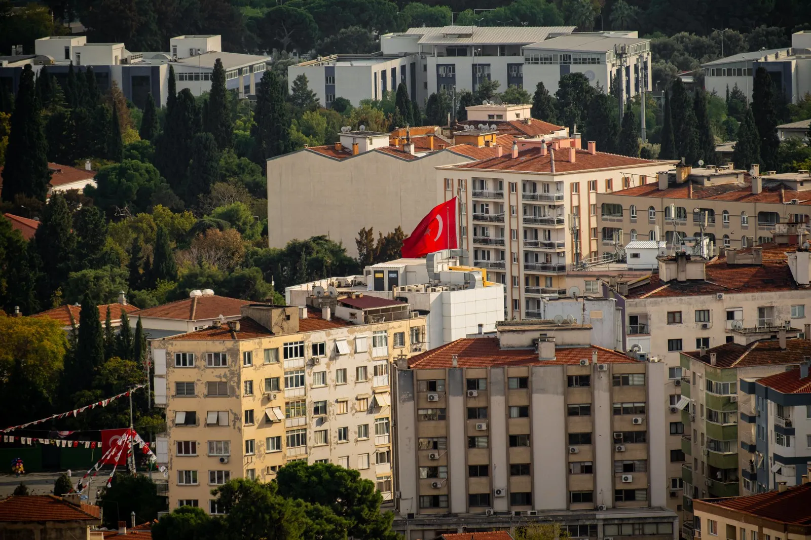 Aerial perspective of Izmir, Turkey, showcasing residential buildings and a prominent Turkish flag.