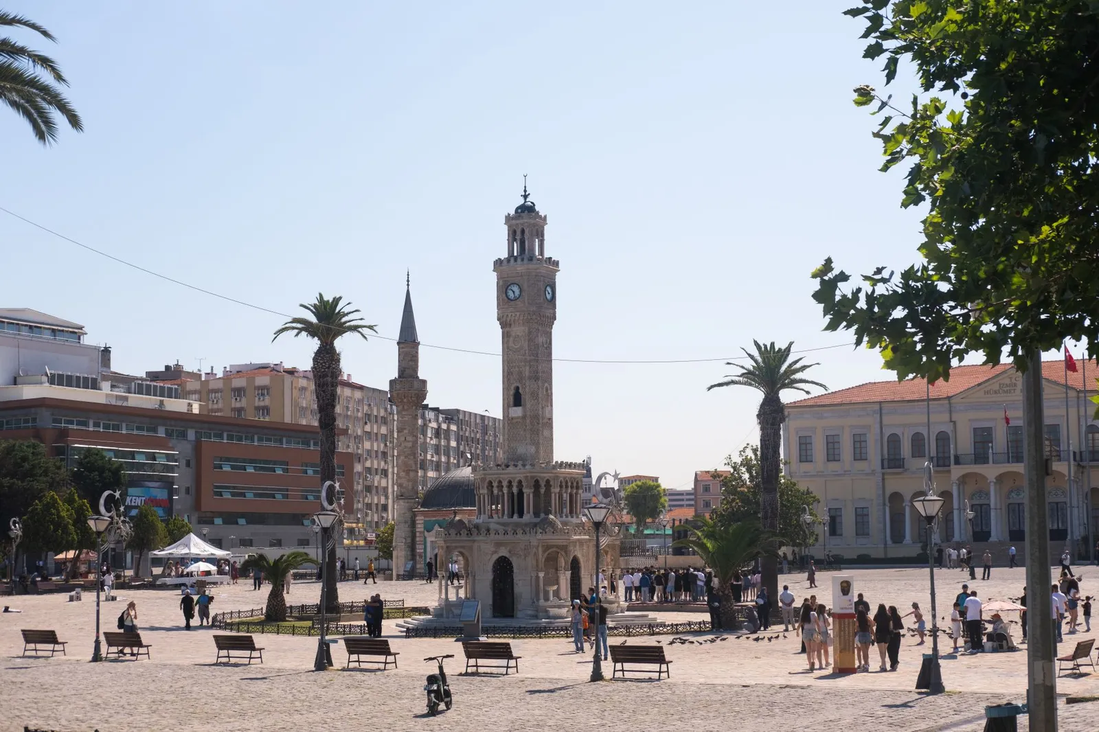 Izmir Clock Tower in Konak Square captured during a sunny day, highlighting iconic architecture and vibrant street life.