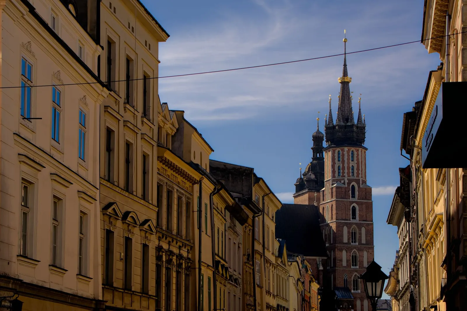 View of St. Mary's Basilica along a historic street in Kraków, showcasing medieval architecture.