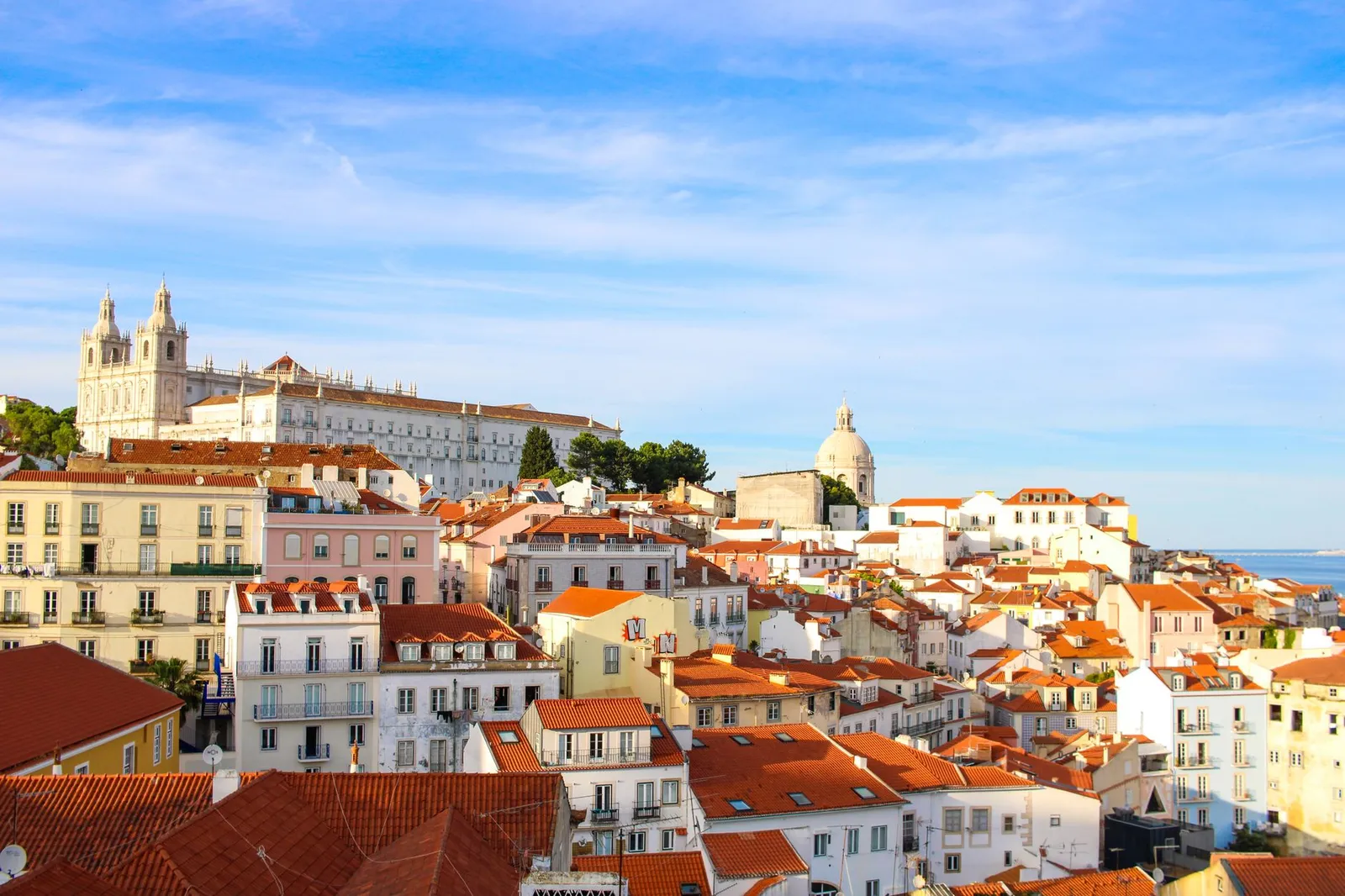 A scenic view over Lisbon's historic Alfama district showcasing traditional architecture under a clear sky.