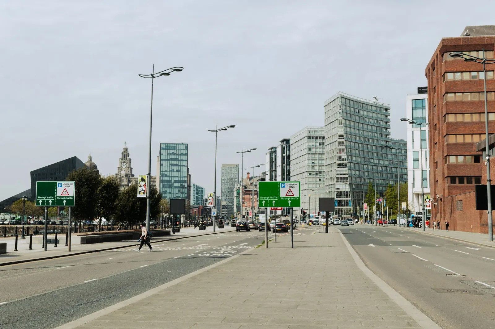 A bustling urban view of Liverpool's downtown with tall modern buildings lining the street.