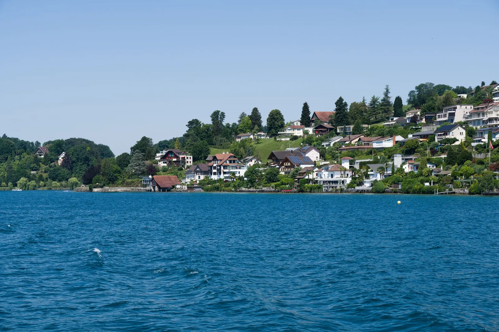 Picturesque landscape of lakefront homes in the Swiss countryside, capturing serene beauty and lush greenery.