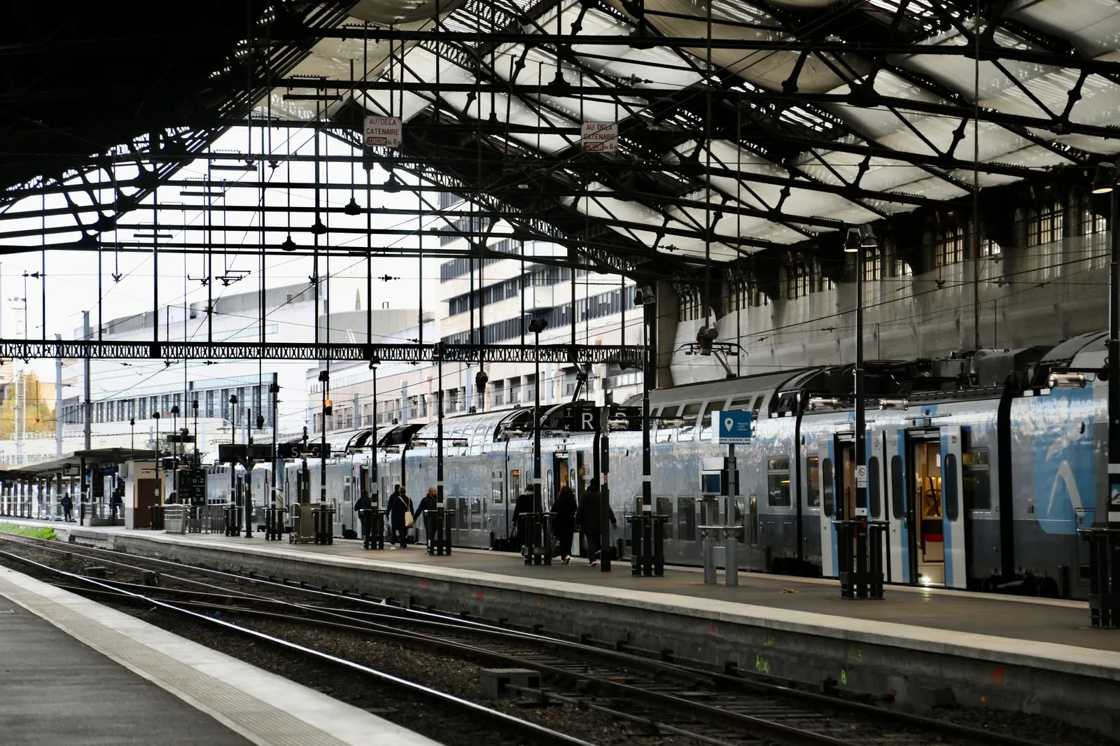 Train station in Paris, France, with people boarding trains. Urban transit scene.