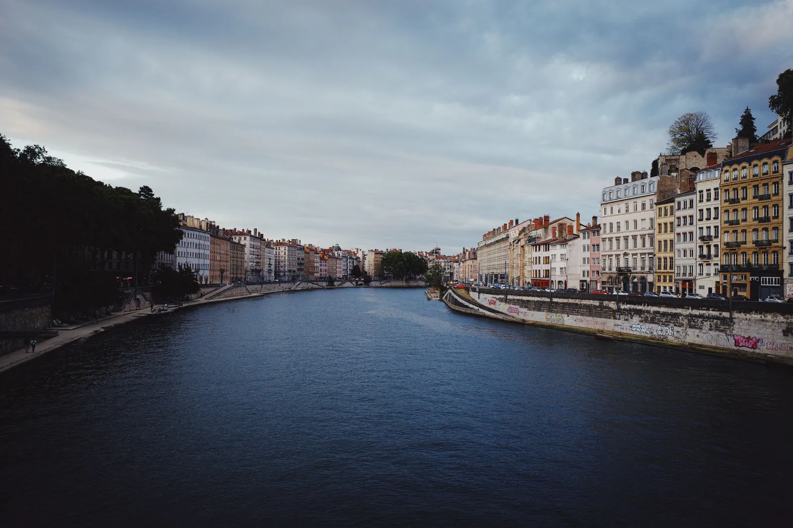 Beautiful riverfront architecture in Lyon, France, under a dramatic sky.