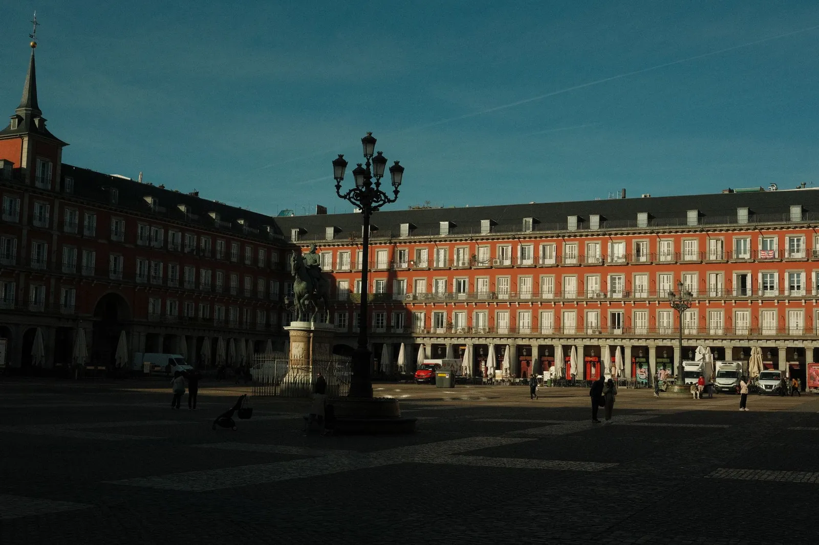 Sunlit view of historic Plaza Mayor in Madrid, showcasing architecture and daily life.