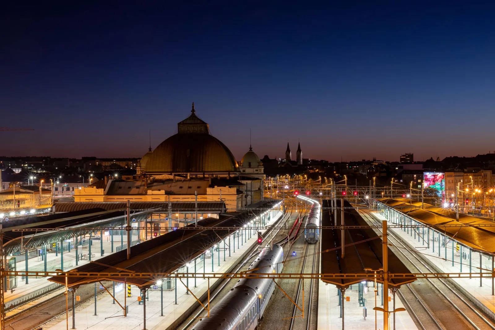 Stunning night view of Plzeň Main Railway Station, showcasing urban architecture and vibrant city lights.