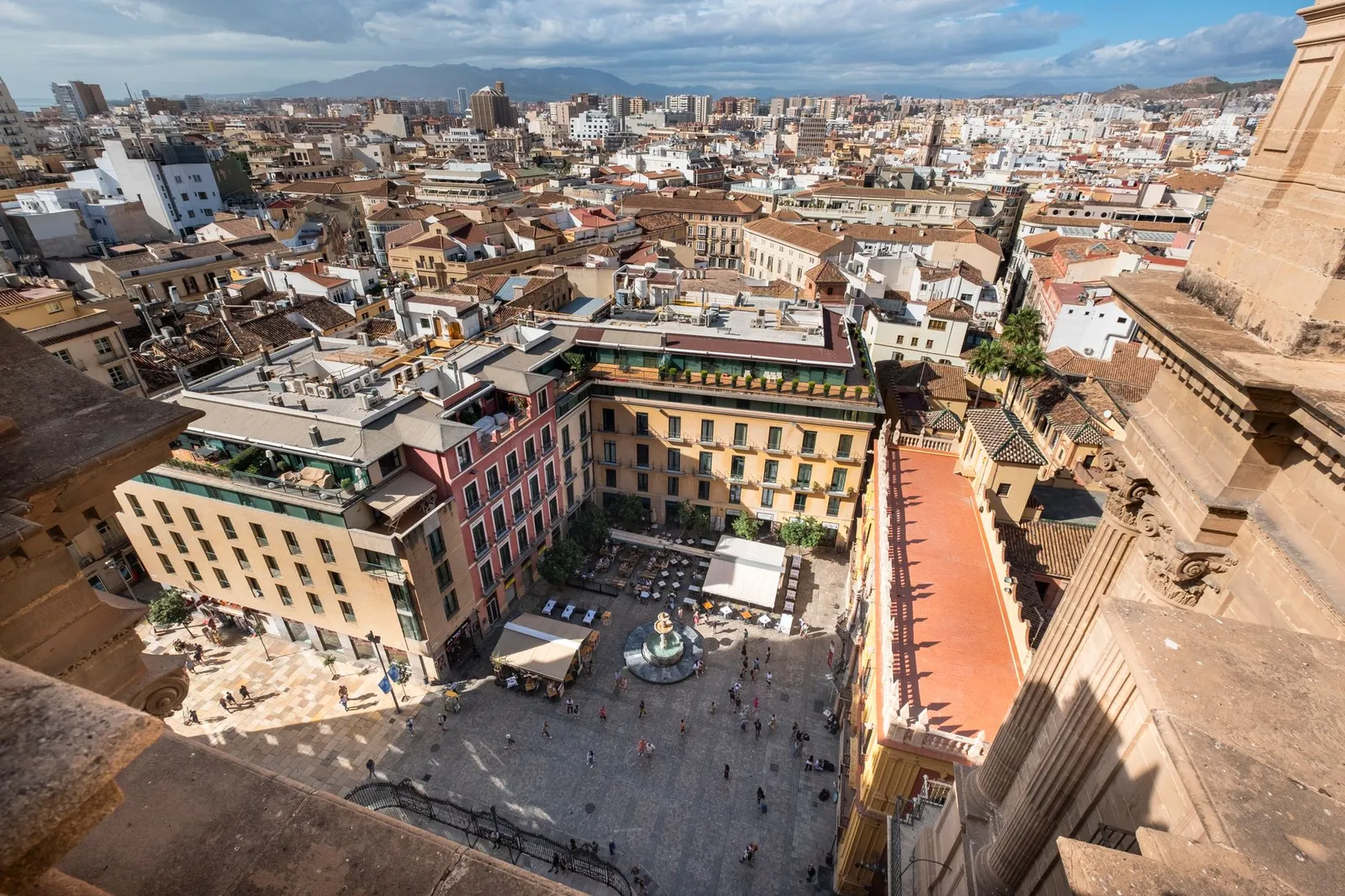 A breathtaking aerial photograph of a bustling plaza in Málaga, Spain, filled with vibrant architecture and life.