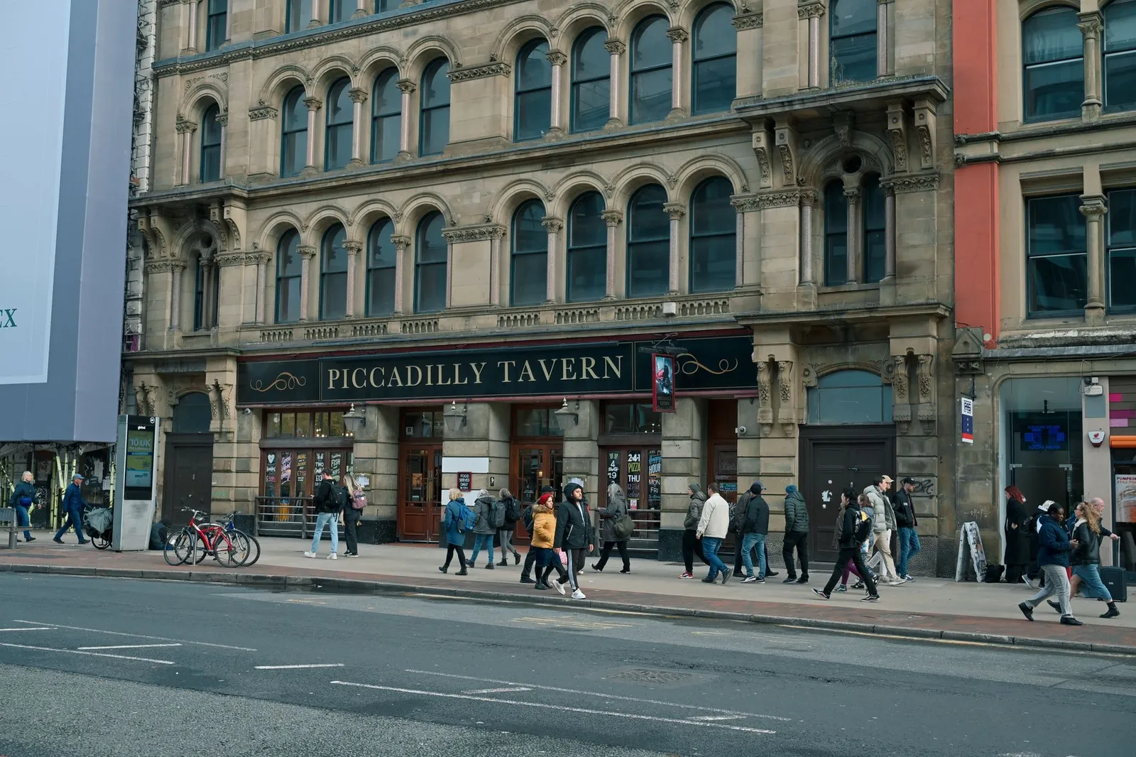 People walking past the historic Piccadilly Tavern in Manchester city center.