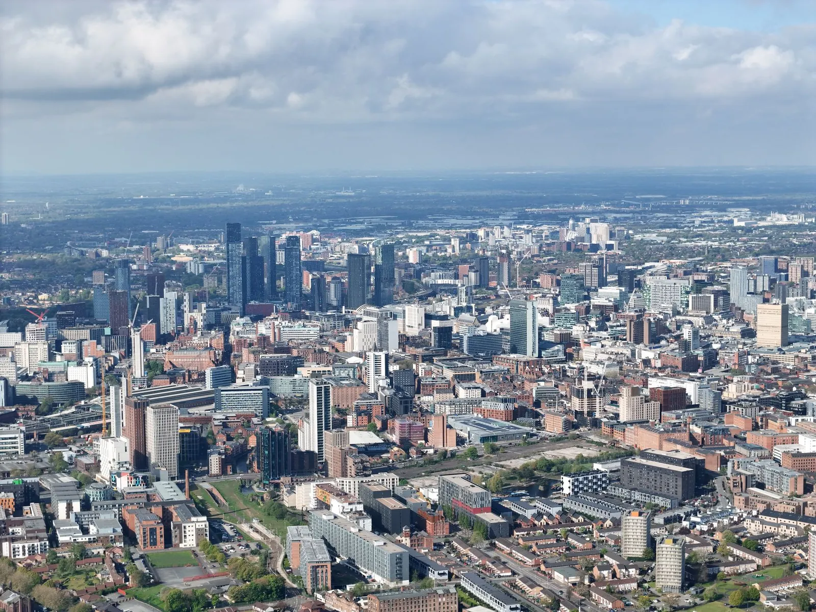 Stunning aerial photograph of Manchester's urban skyline showcasing modern architecture under scattered clouds.