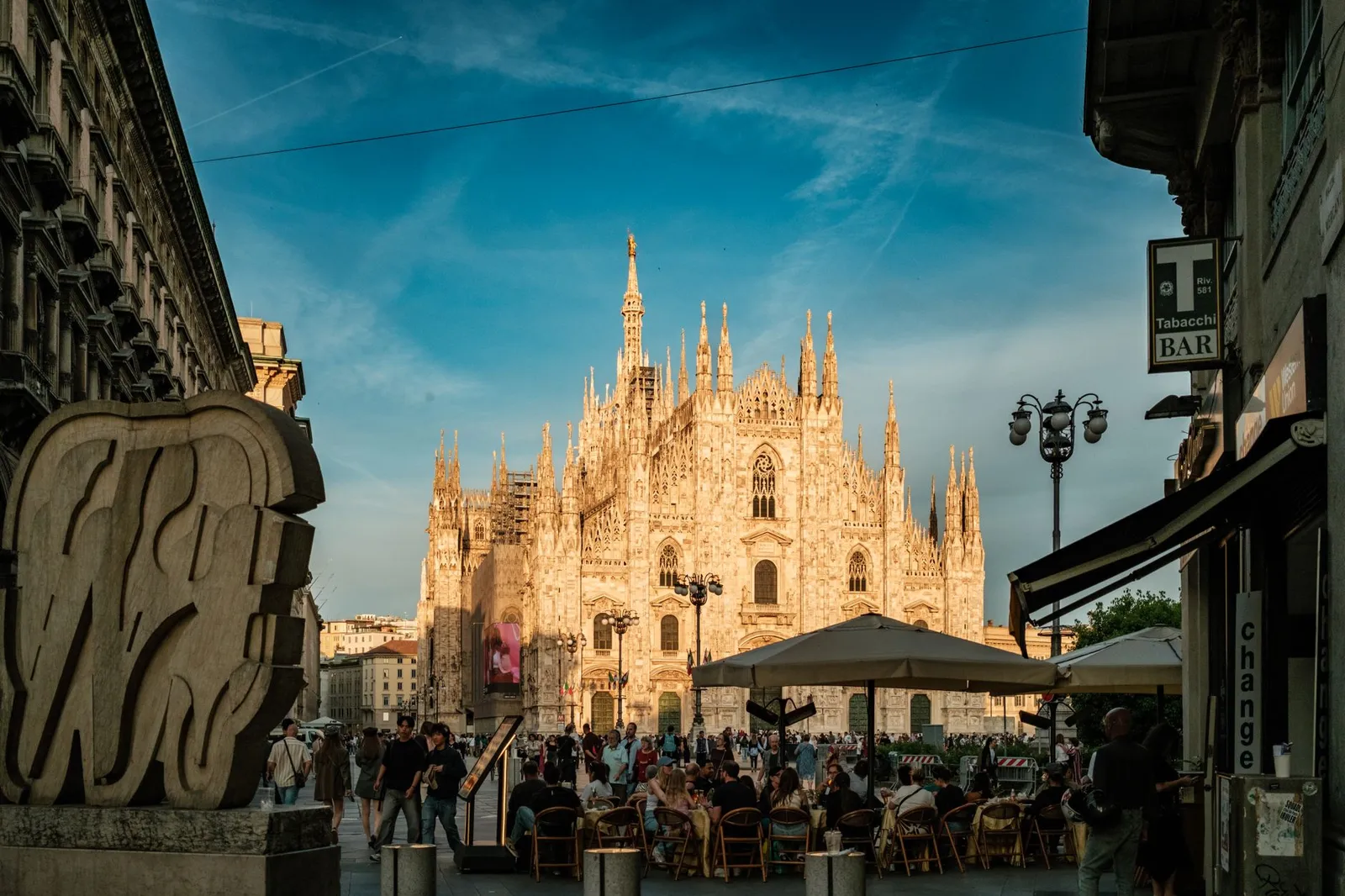 Enjoy a lively evening scene at the Duomo di Milano with bustling crowds and beautiful architecture.