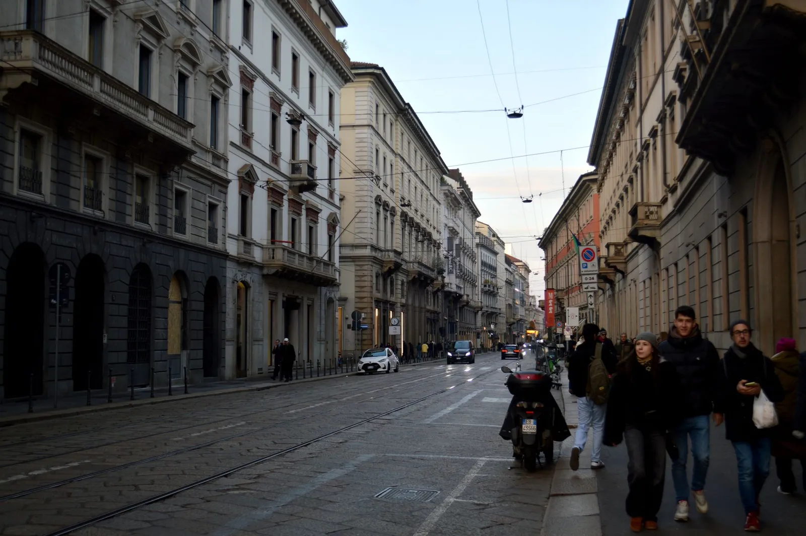 Street view in Milan featuring historical buildings and pedestrians in winter.