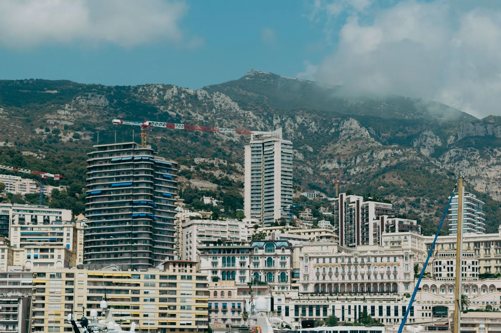 A captivating skyline of Monaco with modern architecture against lush hills under a summer sky.