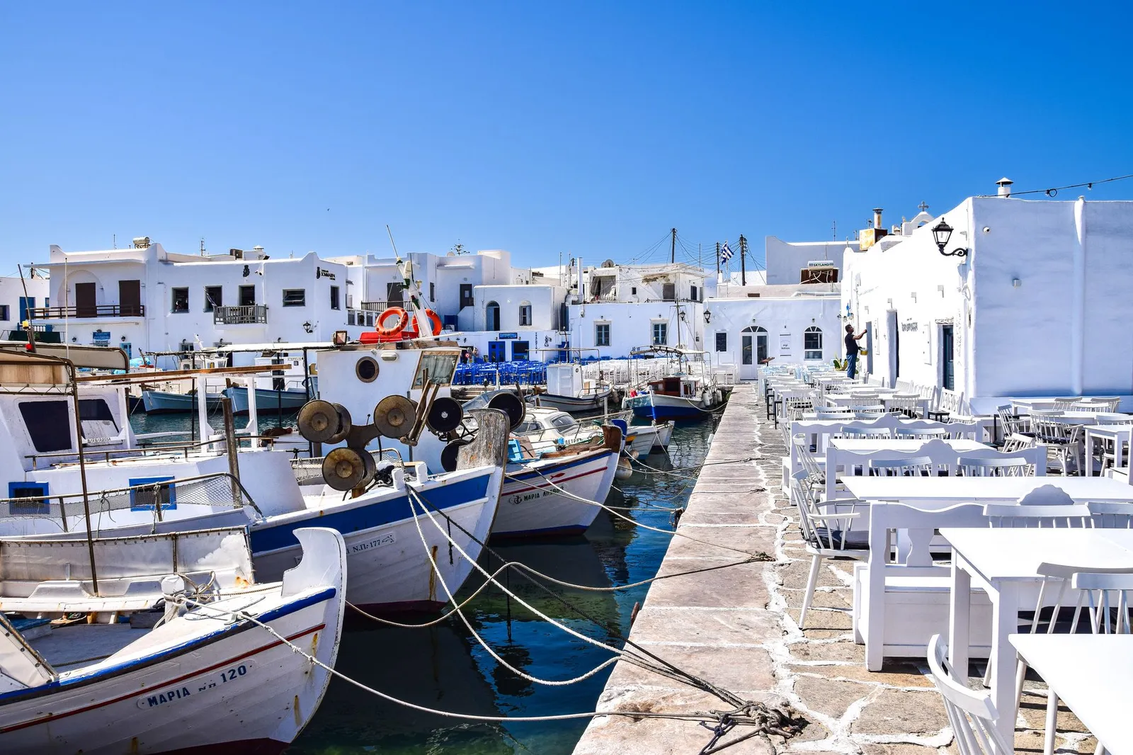 Charming coastal scene with boats and traditional Greek architecture in Paros harbor.