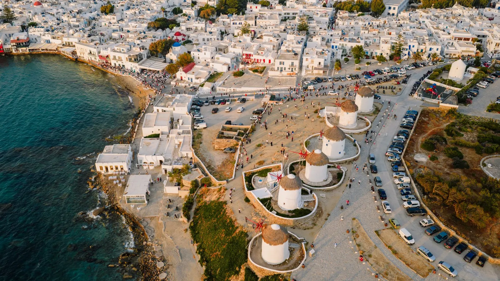 Stunning aerial view of the famous windmills of Mykonos, Greece, at sunset, surrounded by whitewashed buildings.