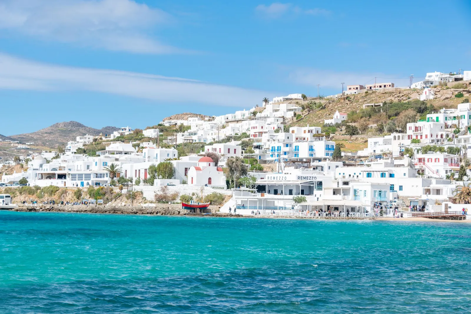 Beautiful view of Mykonos' iconic whitewashed buildings along the vibrant turquoise coast.