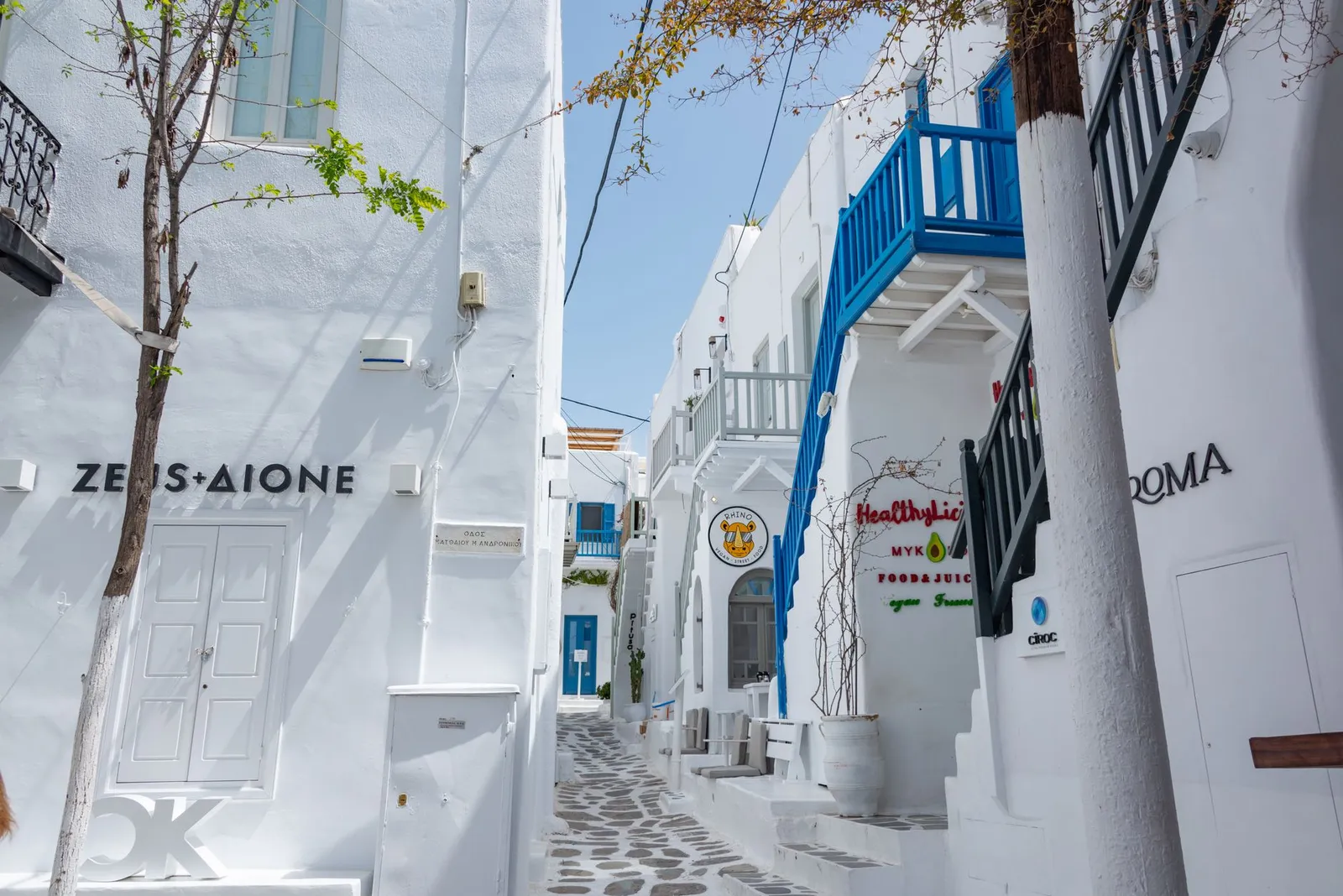 Charming narrow alley in Mykonos with traditional white architecture and vibrant blue accents.