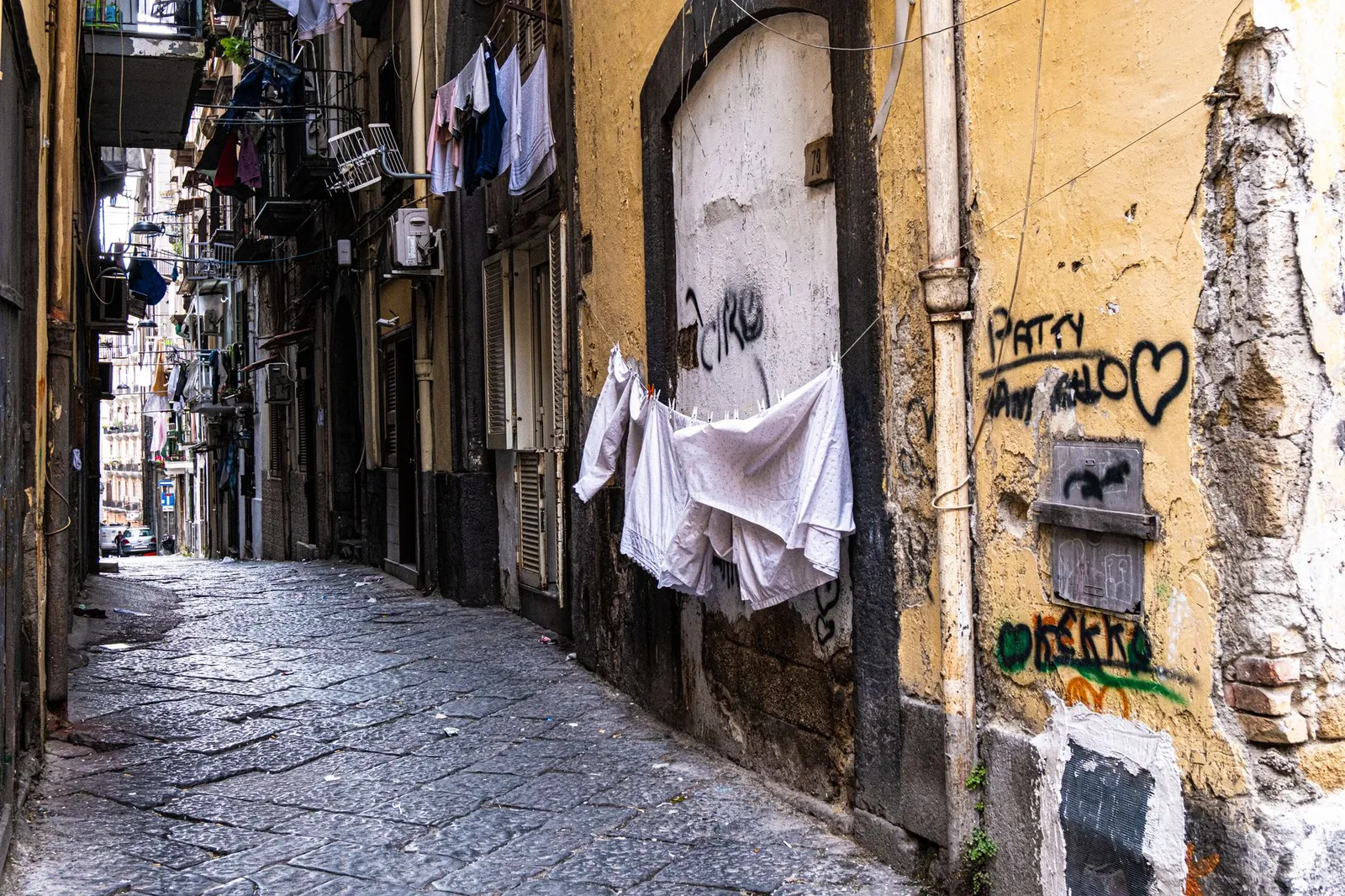 Colorful laundry and graffiti on a narrow street in Naples, Italy. Capturing everyday urban life.