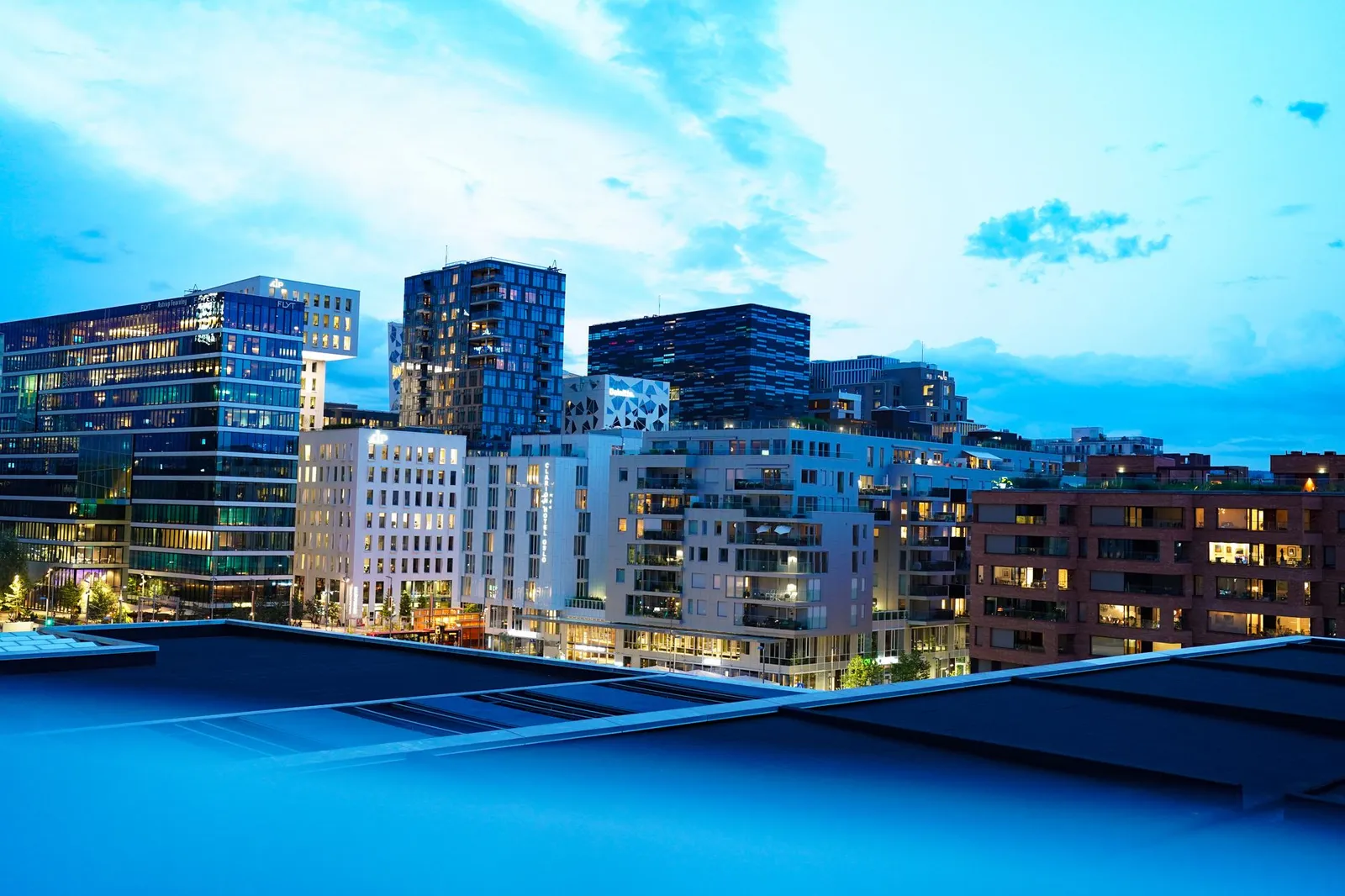 Illuminated modern buildings in Oslo's downtown at twilight, showcasing architecture.