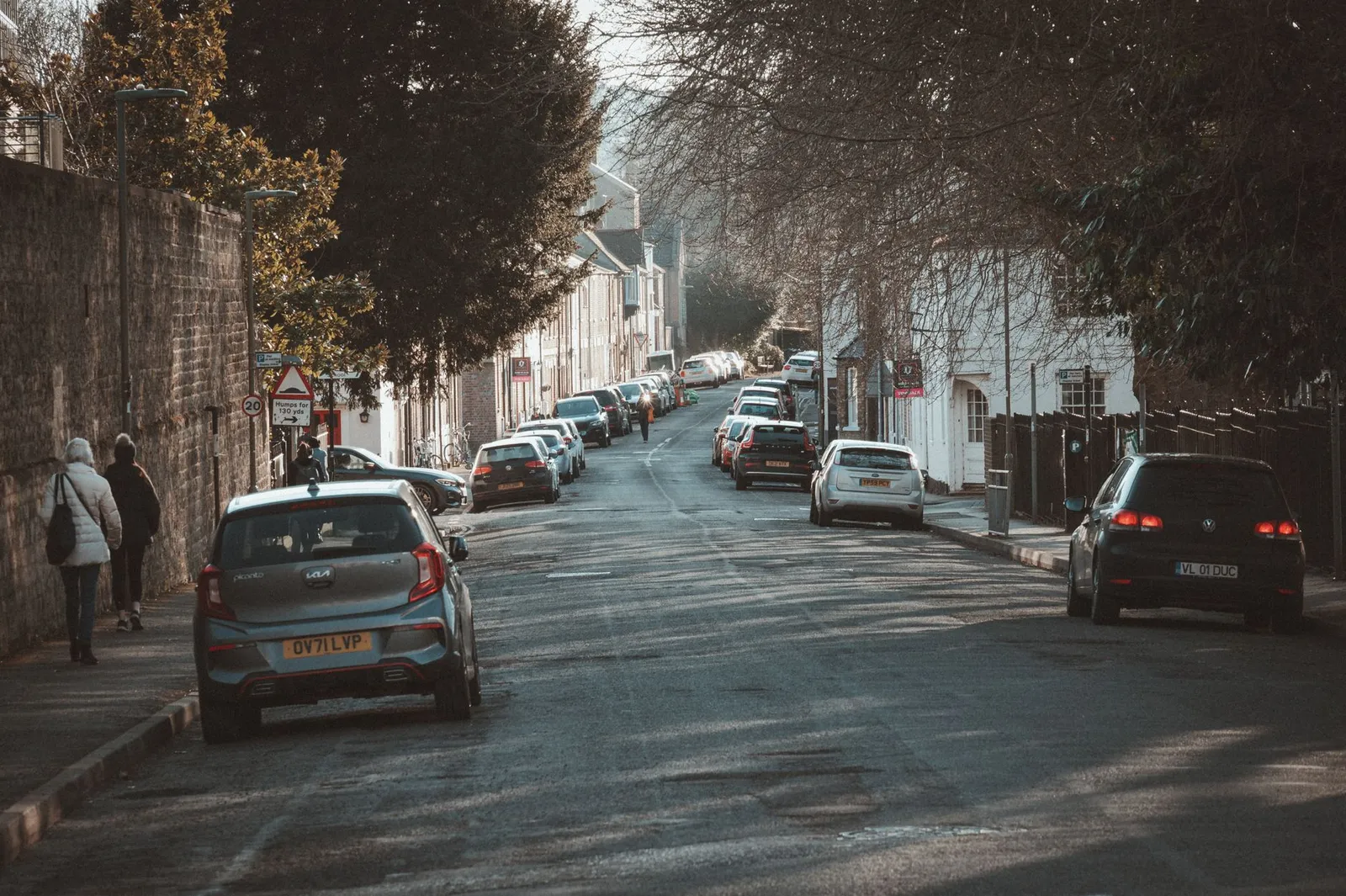 Peaceful street in Oxford, England with parked cars and pedestrians on a calm day.