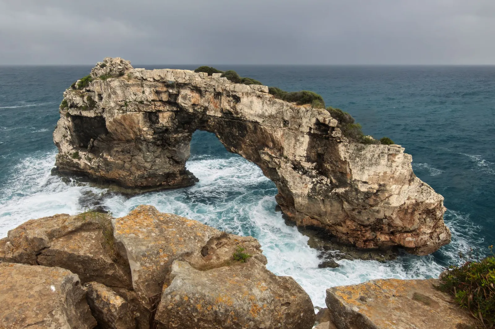 Captivating view of the rugged natural arch and azure waters at Cala Santanyí, Spain.