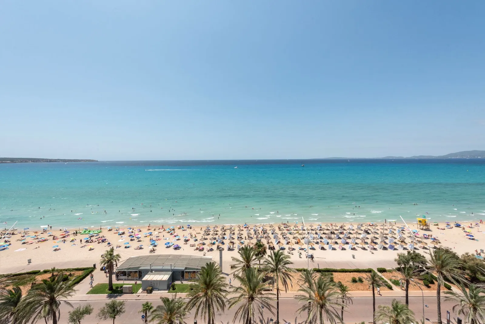 Aerial view of sunbathers on a vibrant Palma beach in summer.