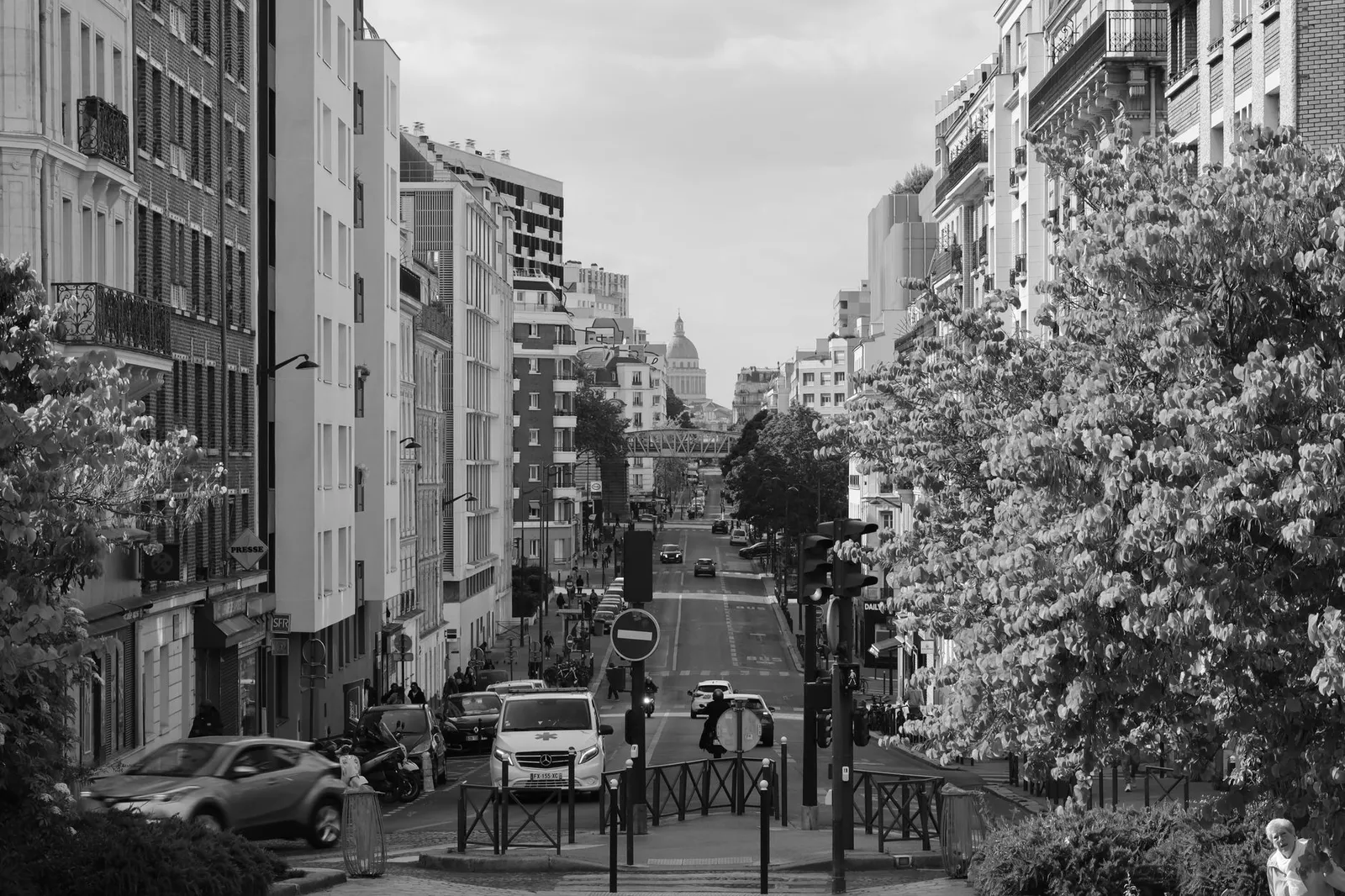 Black and white street view of Paris with iconic landmark in the distance.