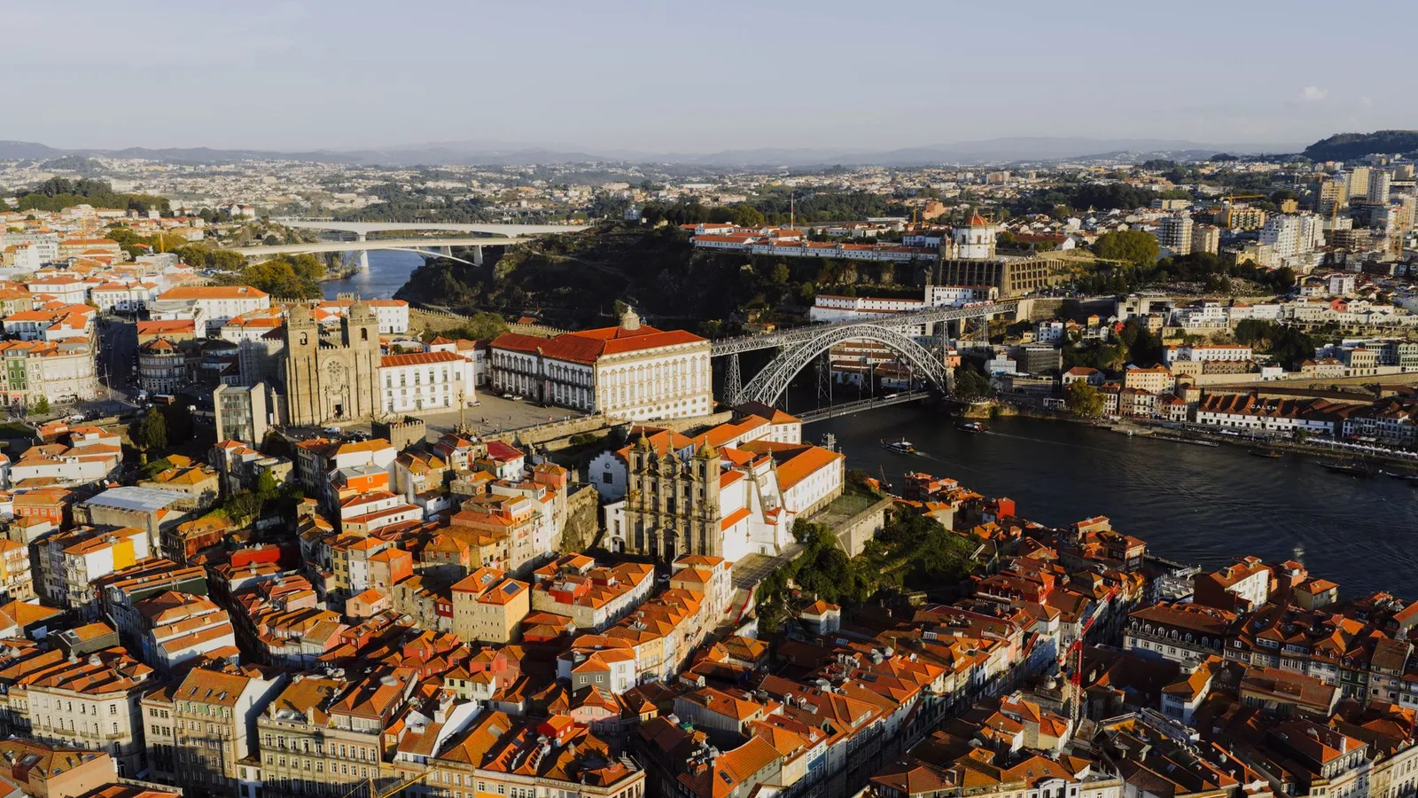 Stunning aerial shot of Porto, Portugal at sunset, showcasing the iconic Dom Luís I Bridge and historic architecture.