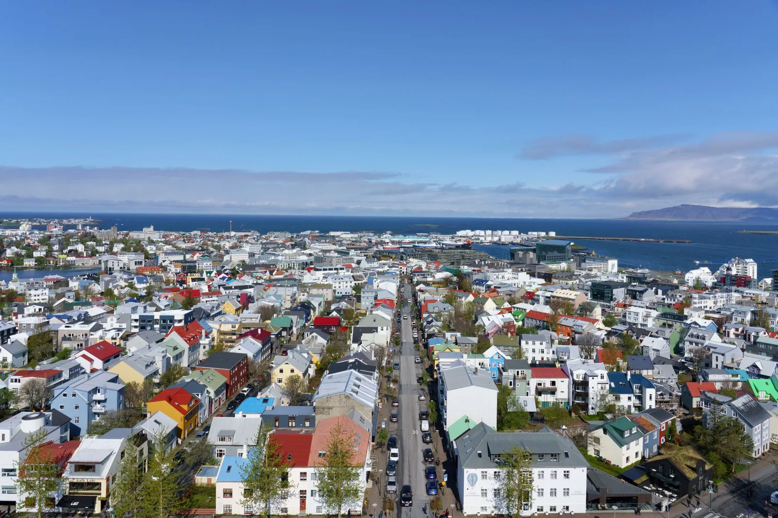 Vibrant aerial view of Reykjavik, Iceland, showcasing colorful rooftops and ocean backdrop under a clear sky.