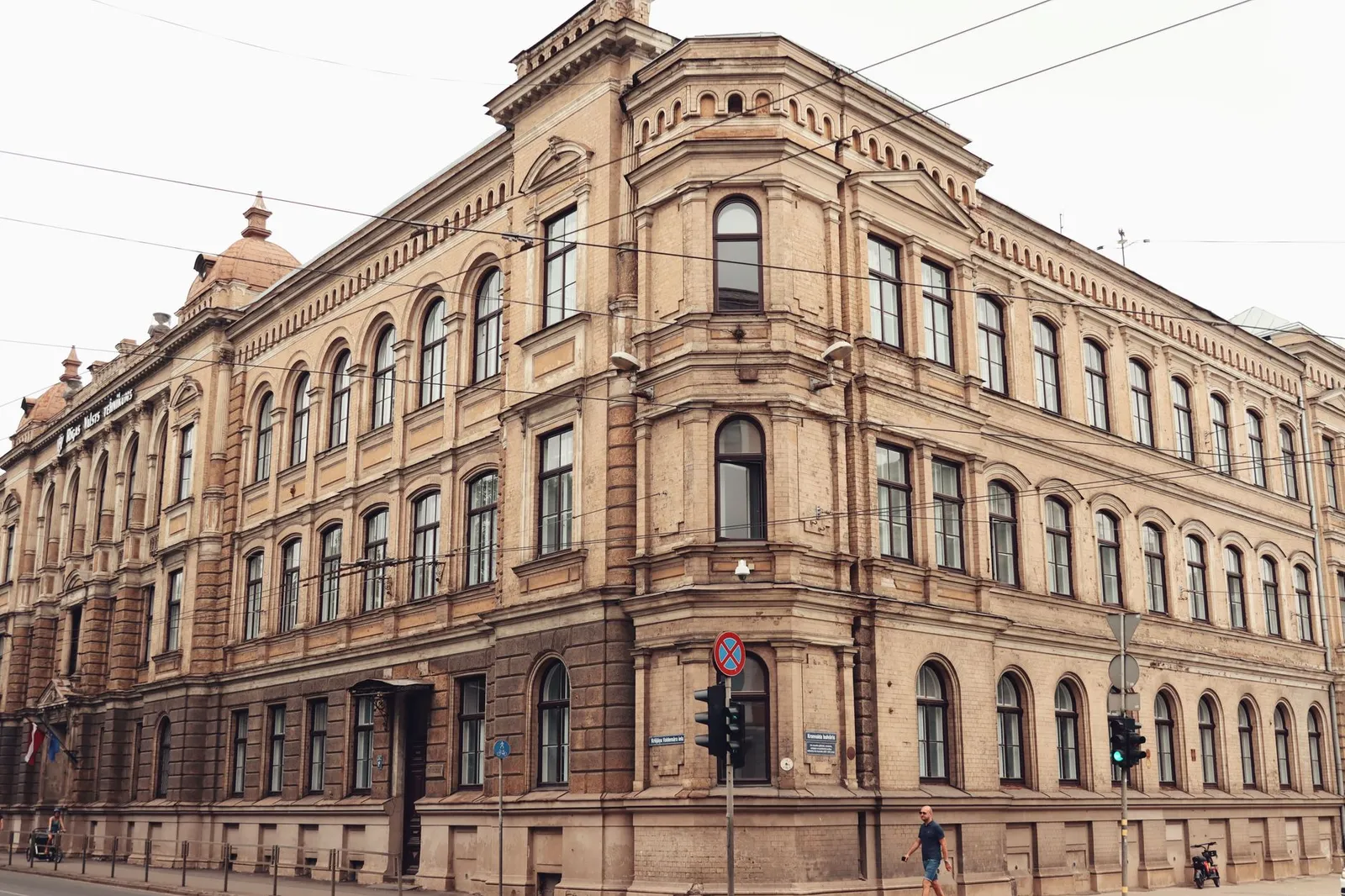 Elegant historic building facade in Riga's old town with a person walking by.