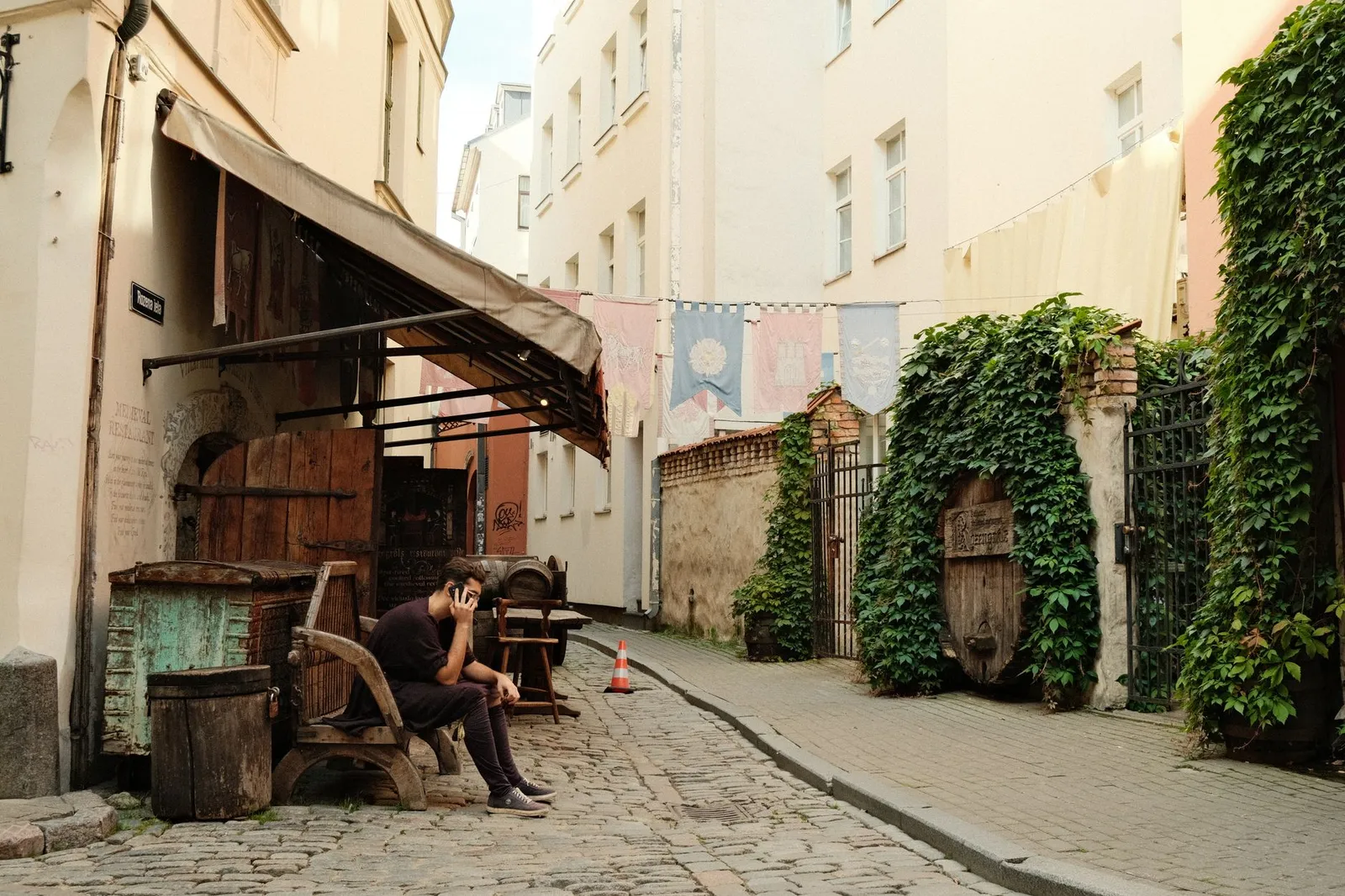 A quiet, cobblestone street scene with a person on a phone, capturing Riga's historical charm.