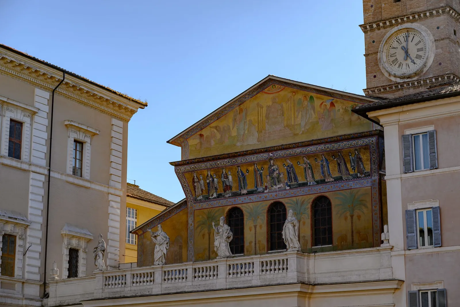 Close-up of the facade of Santa Maria in Trastevere showcasing Romanesque details and a clock tower.
