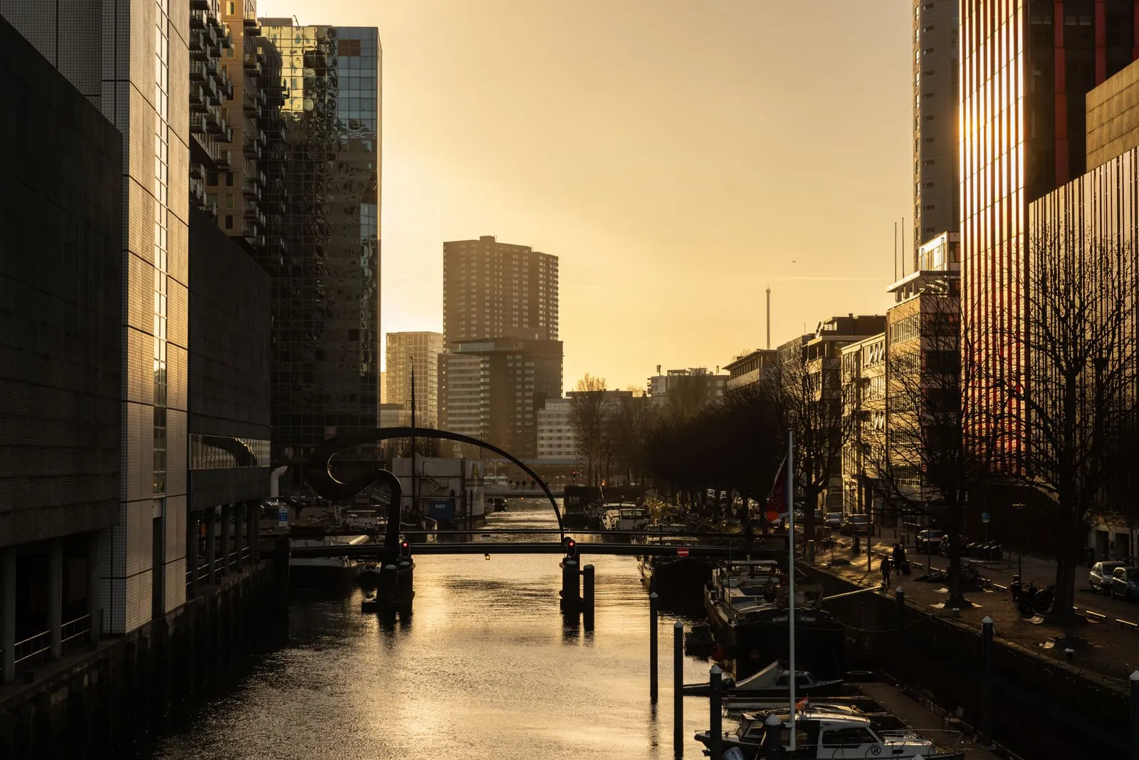 Captivating sunset over a canal in Rotterdam, Netherlands, showcasing modern architecture and reflections on water.