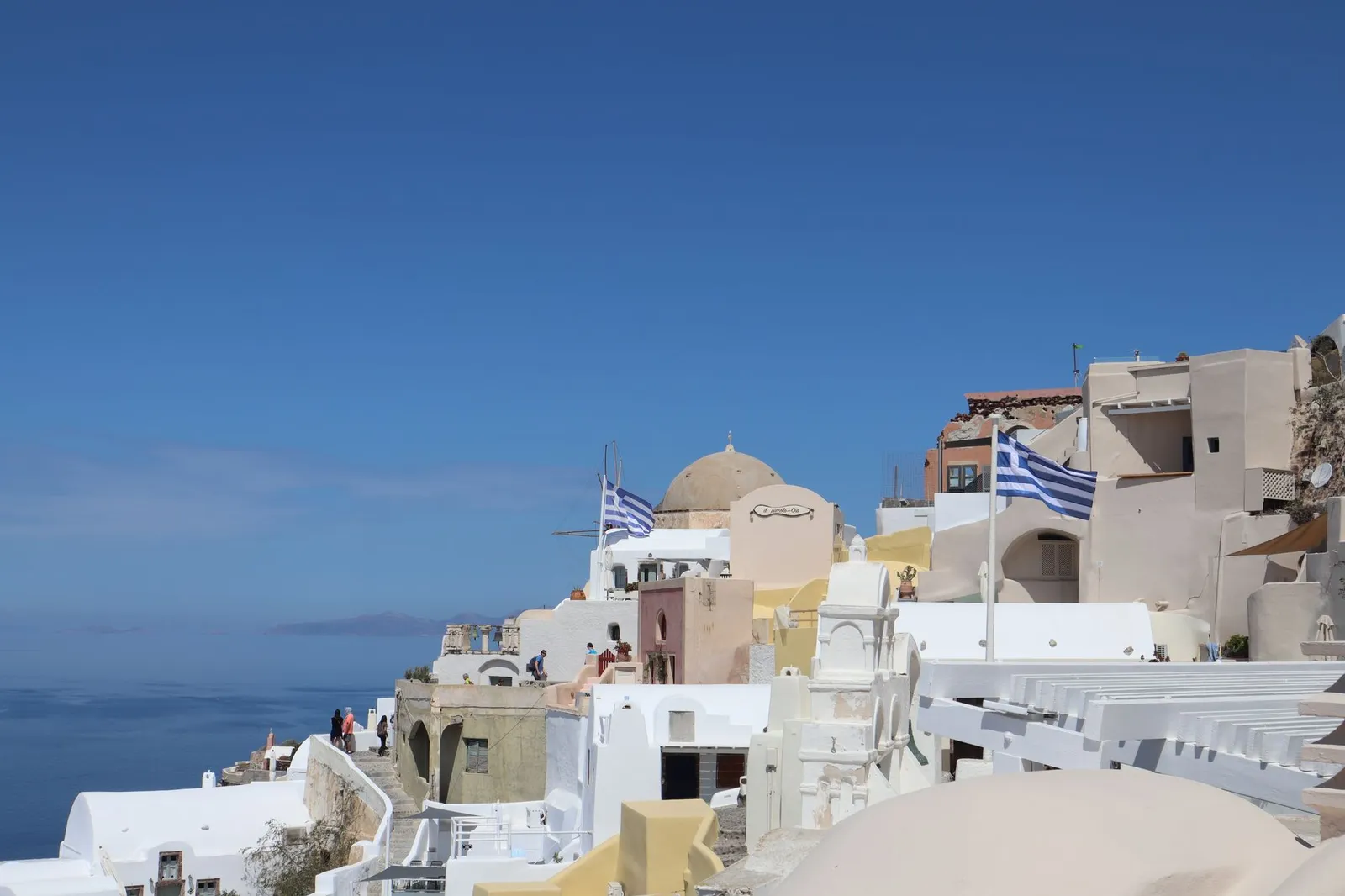 Breathtaking Santorini village of Oia with iconic Greek architecture and flags.