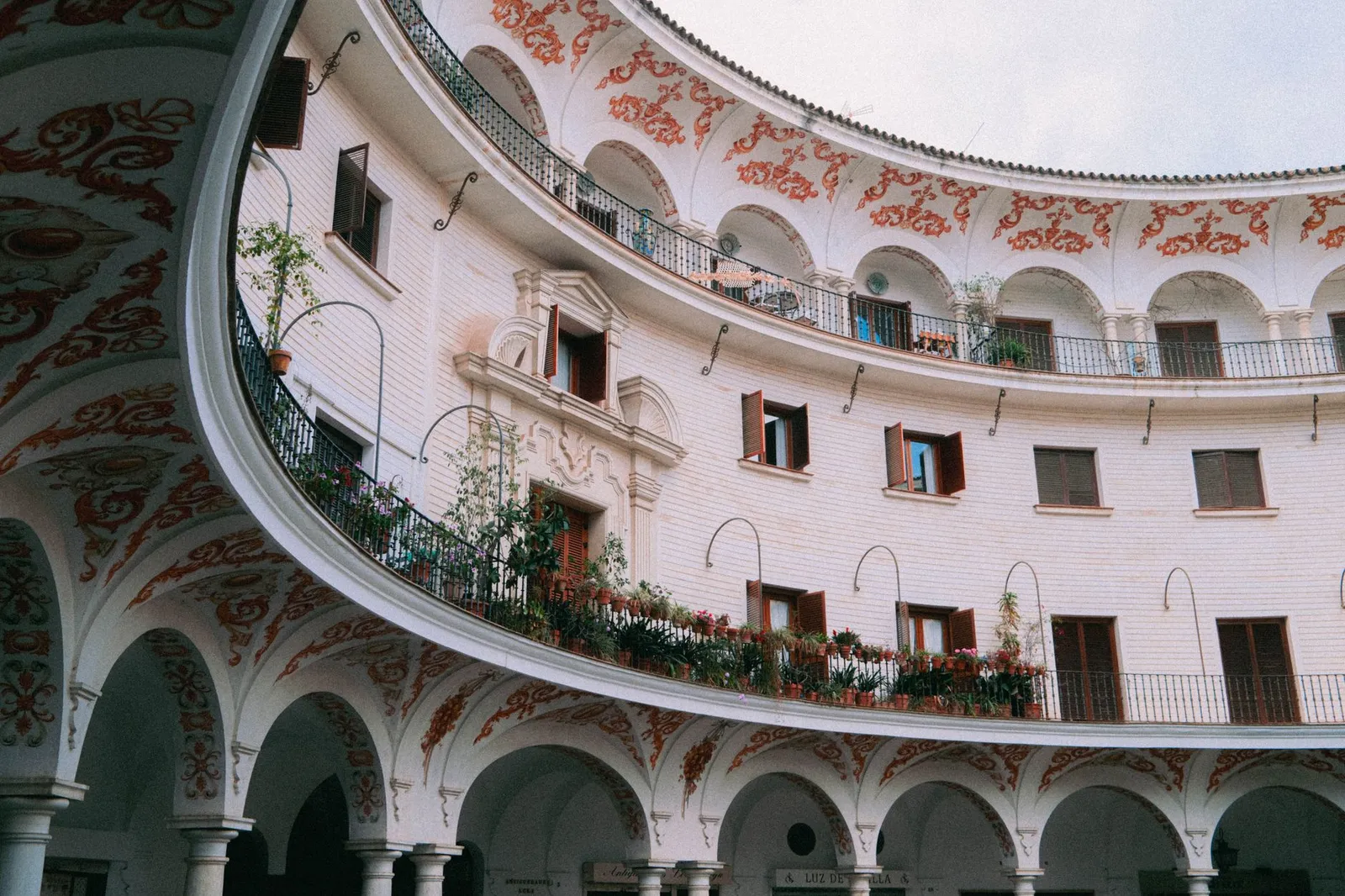 Elegant circular courtyard with ornate arches and balconies in Seville, Spain.