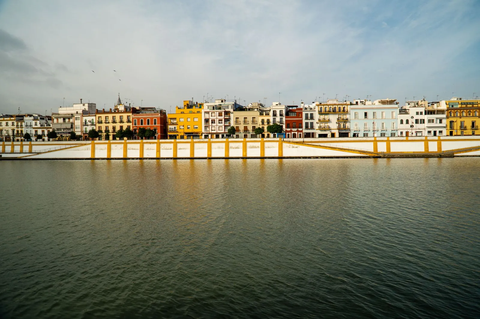 Vibrant homes along the river in Seville, showcasing a colorful urban landscape.