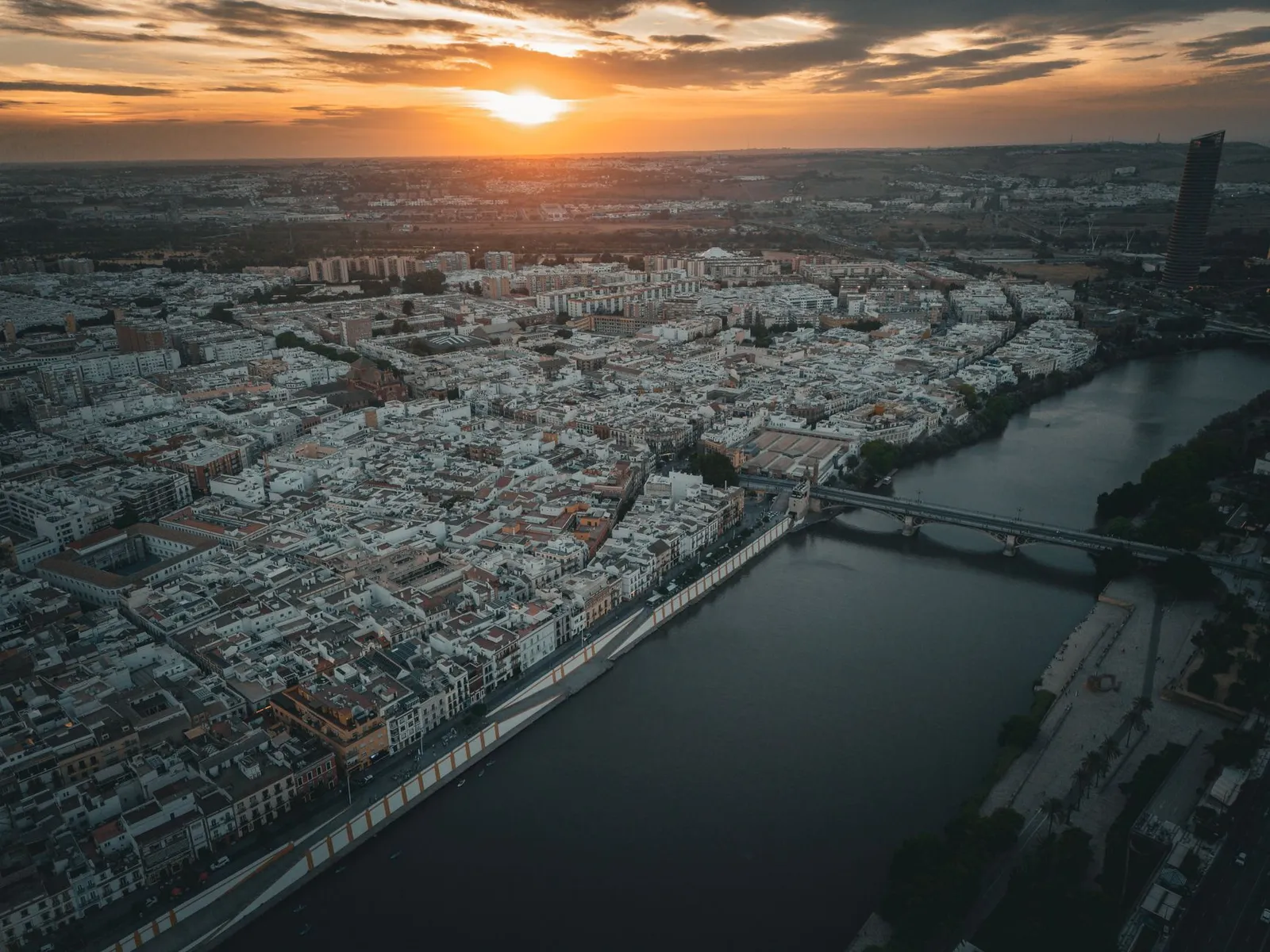 Stunning aerial view of Seville, Spain at sunset showcasing the city's architecture and river.