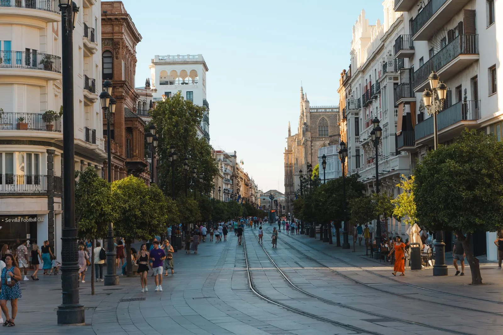 Vibrant day on a bustling street in Seville, showcasing the city's architecture and lively atmosphere.