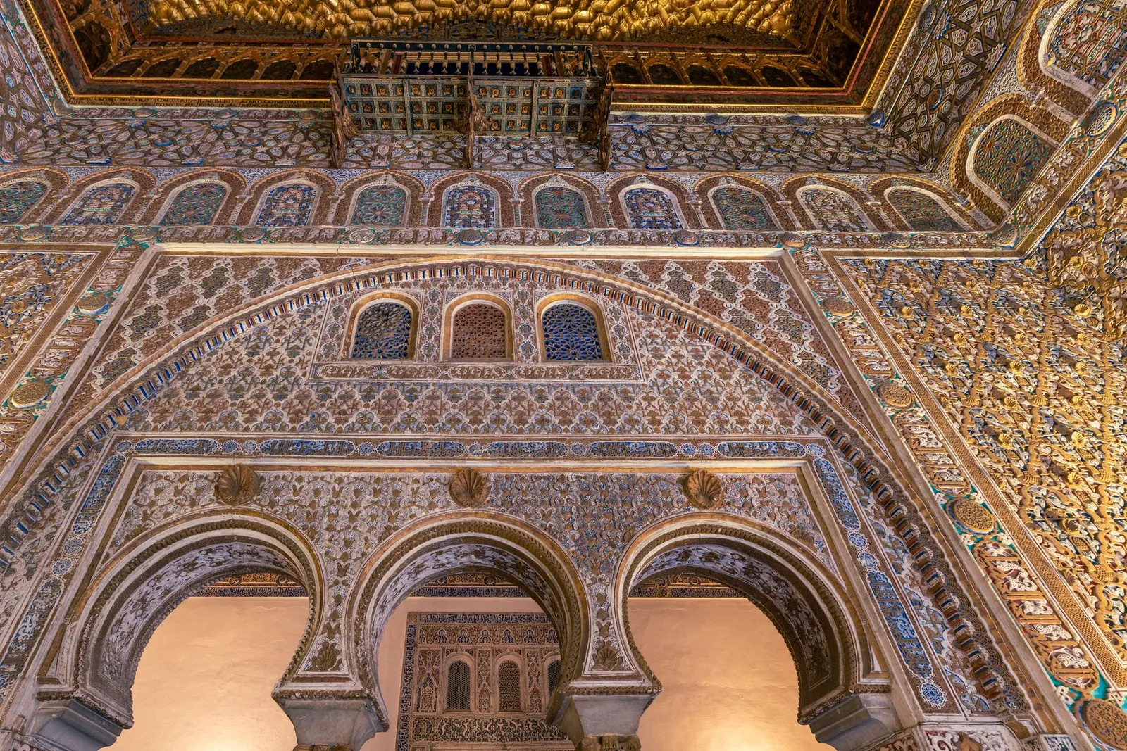 Explore the ornamental arches and ceilings of Seville's Real Alcázar, showcasing stunning Mudéjar architecture.