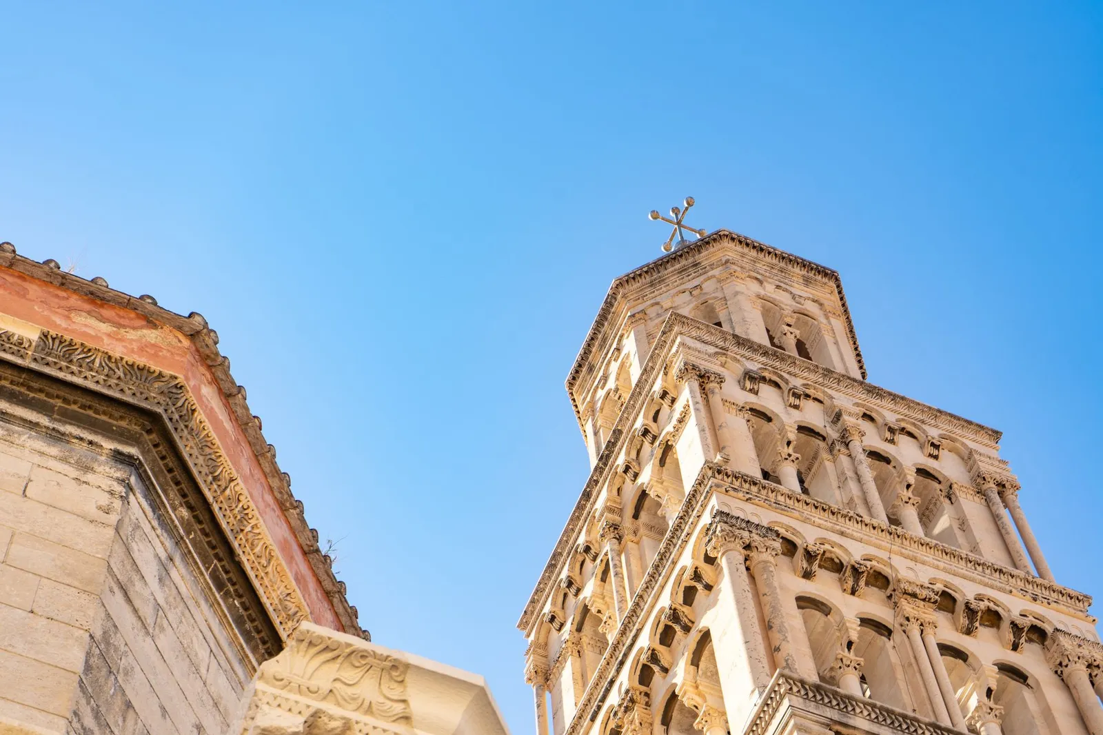 Detailed view of a historic tower in Split, Croatia against a clear blue sky.