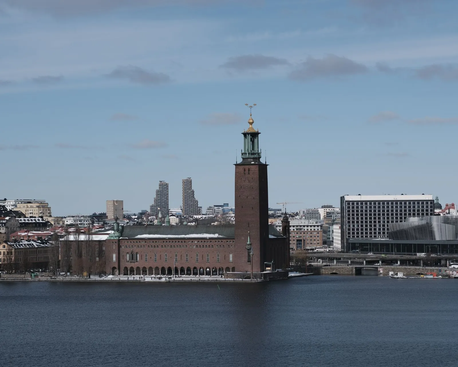 Iconic Stockholm City Hall by the waterfront on a clear winter day with a cityscape backdrop.