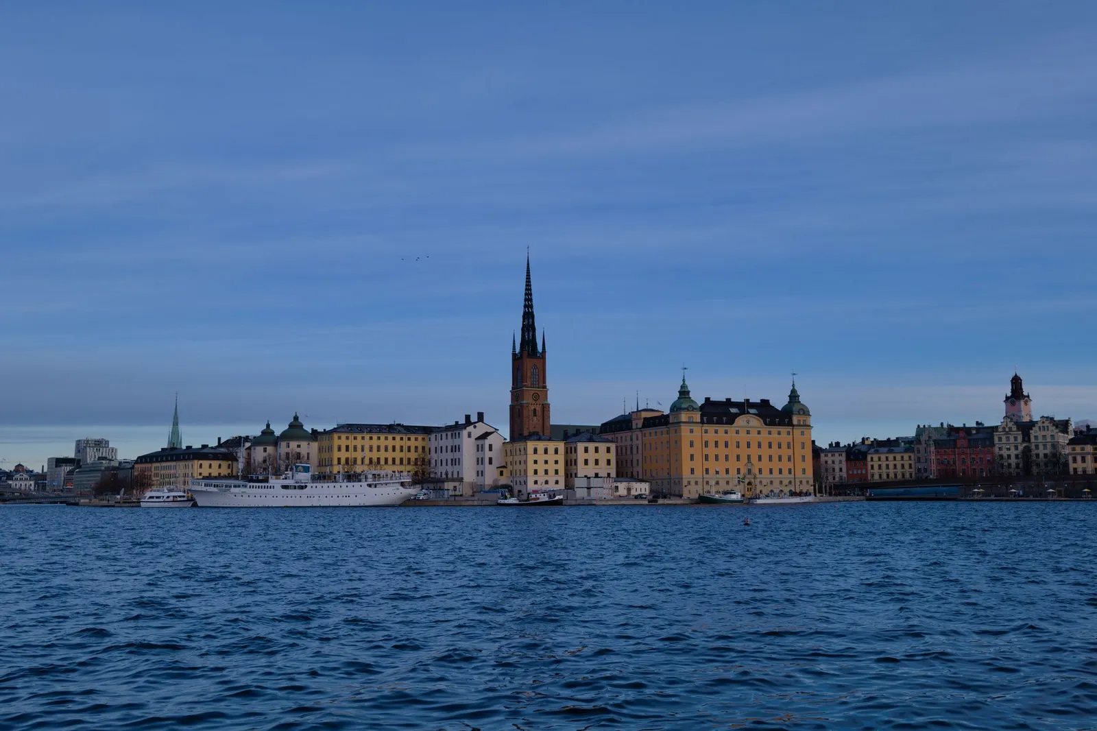 Skyline of Stockholm with historic architecture reflecting on water under a clear sky.