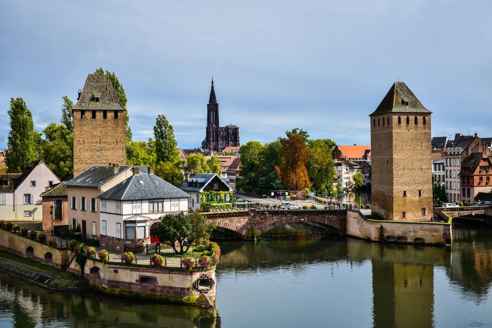 A scenic view of Strasbourg featuring Ponts Couverts and the cathedral in the background.