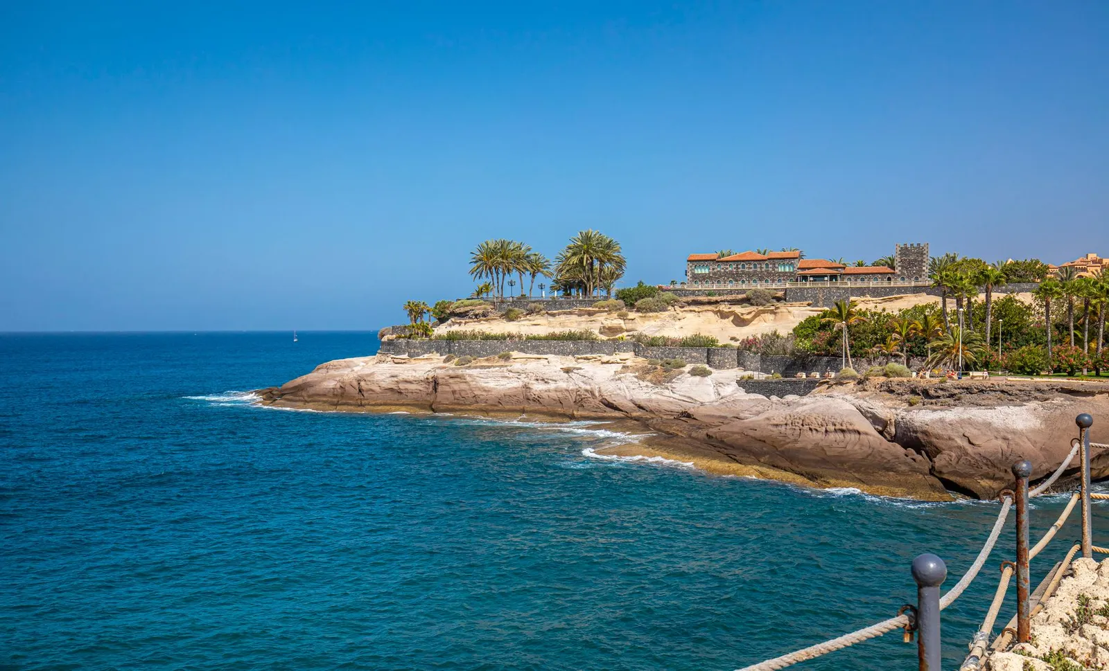 Beautiful coastal scenery at Costa Adeje, with clear blue waters and rocky cliffs under a sunny sky.